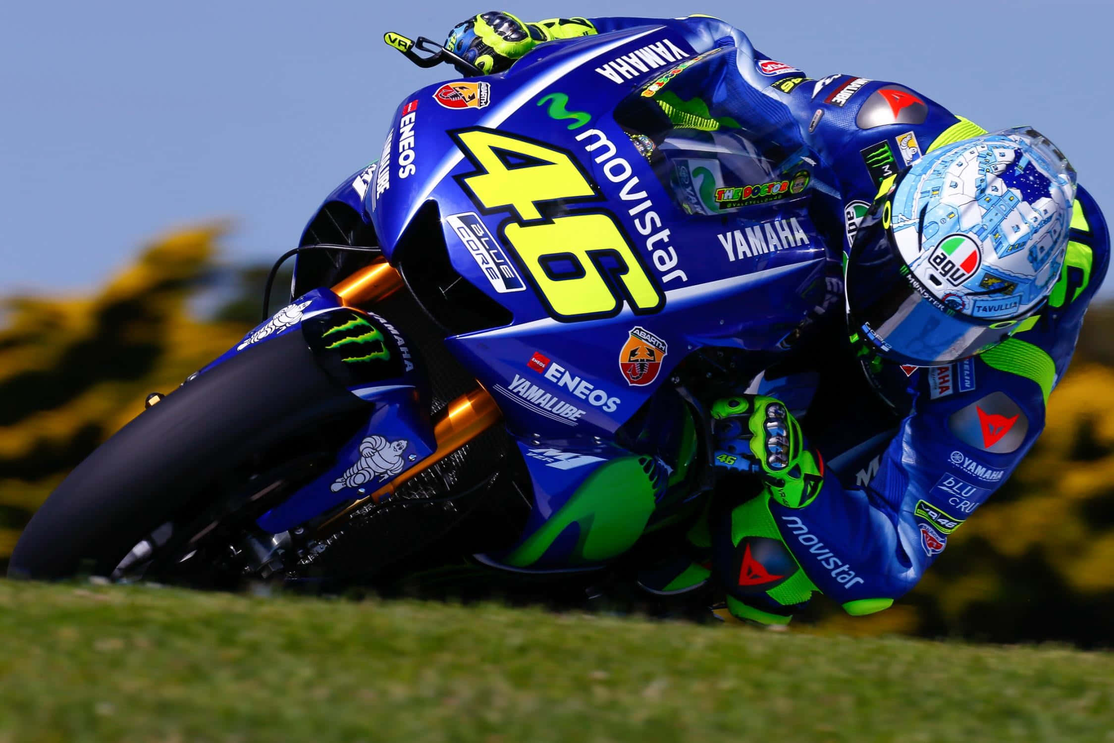 VR46 2017年菲利普島測試賽駕駛 壁紙 — 在陽光明媚的比賽中，一名電單車車手騎著藍綠色46號Yamaha電單車急劇傾斜入彎。