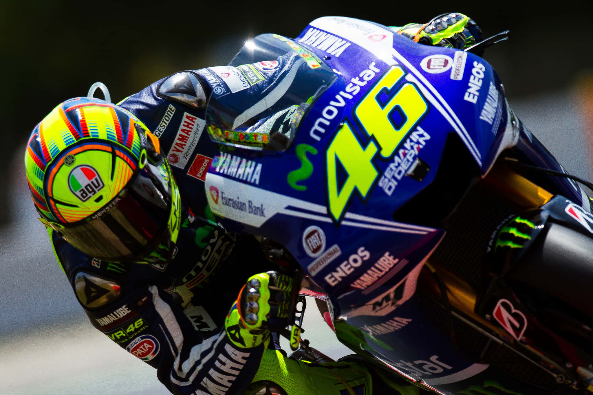 VR46 駕駛藍色雅馬哈Movistar賽車於馬來西亞賽道 壁紙 — 一名電單車賽車手在高速比賽中，騎著藍色Yamaha電單車（號碼46）傾斜入一個急彎。