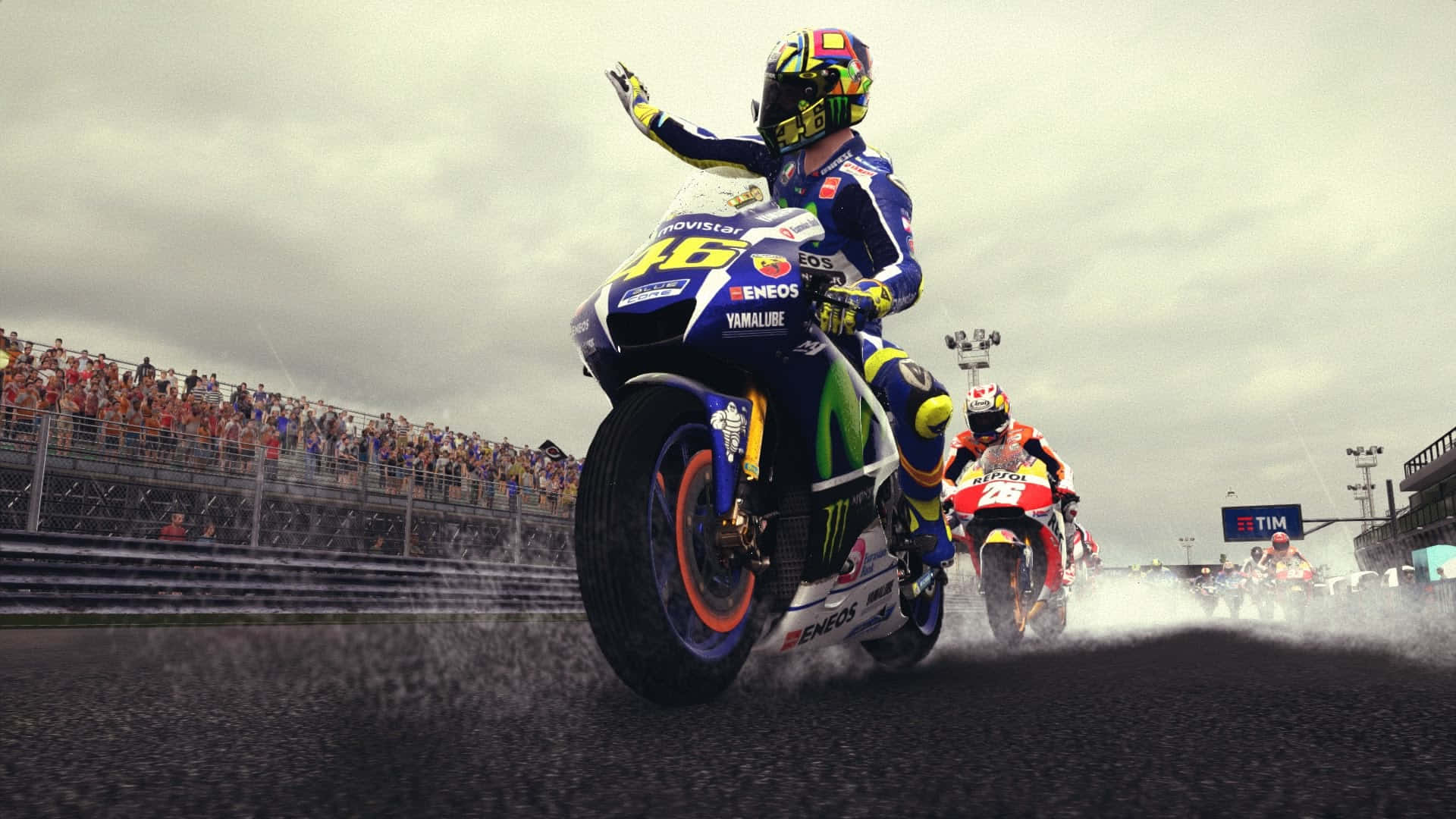 VR46瓦倫蒂諾·羅西遊戲封面 壁紙 — 一名身穿藍色裝備的電單車賽車手在濕滑賽道上慶祝，比賽期間後輪濺起水花。
