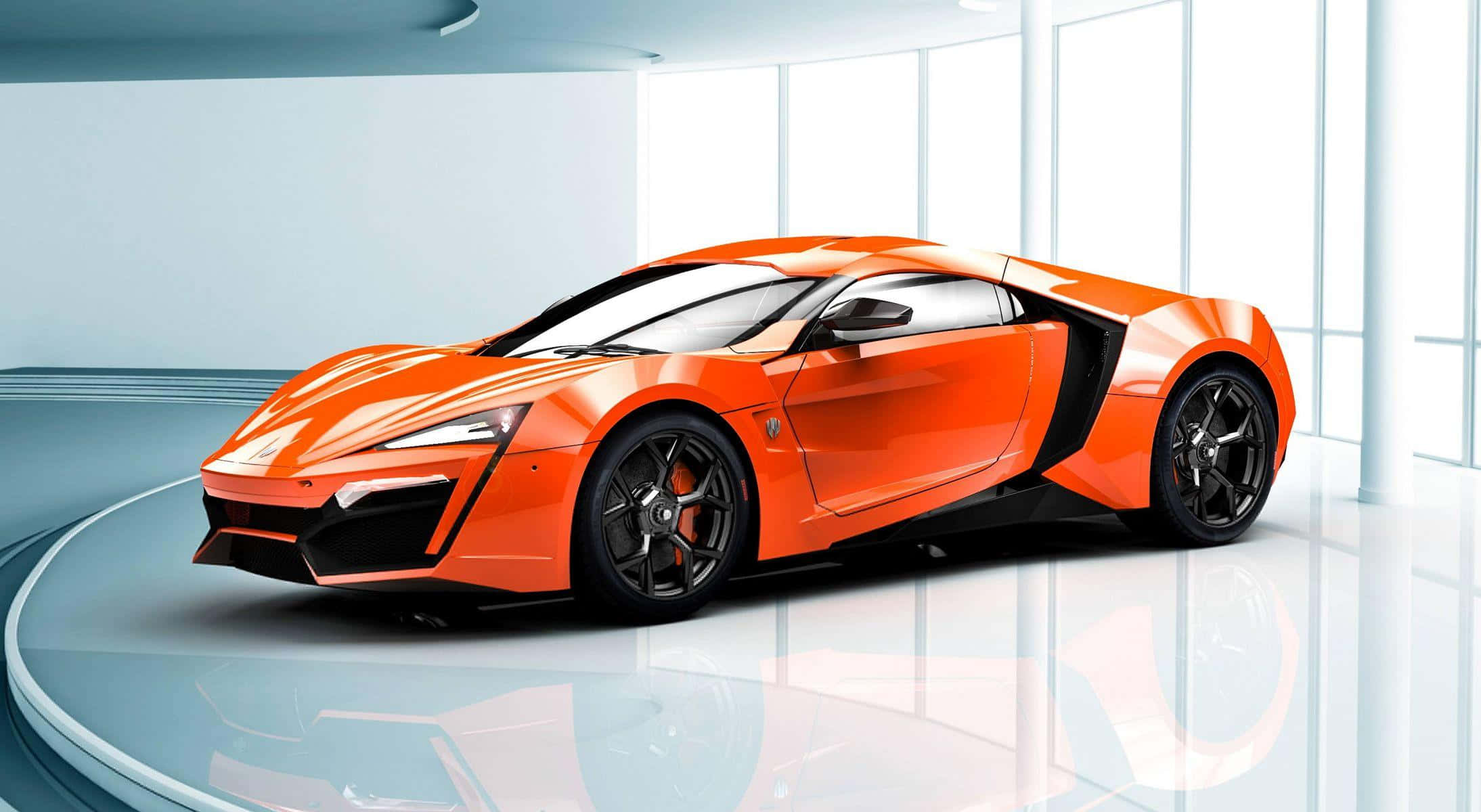 全球十大汽車：橙色W Motors Lykan HyperSport 壁紙 — 一輛充滿活力的橙色跑車帶有黑色點綴，在明亮的攝影棚燈光下於反射圓形平台上閃耀。