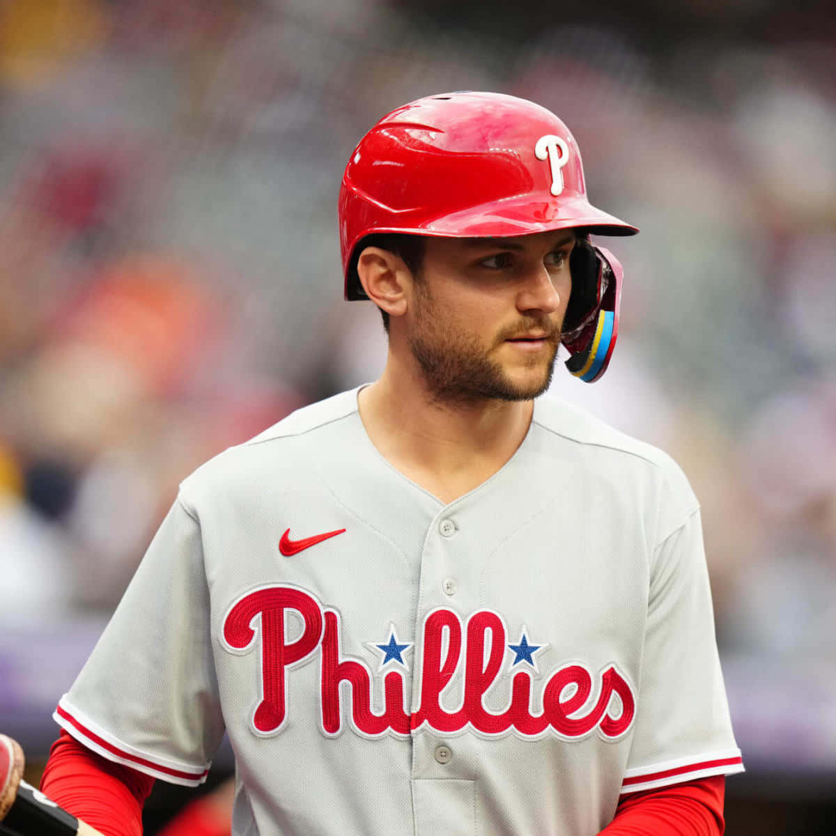 Trea Turner Phillies 桌布 壁紙 — 一位費城費城人棒球選手戴著紅色頭盔、穿著灰色球衣，在日間比賽中專注站立。