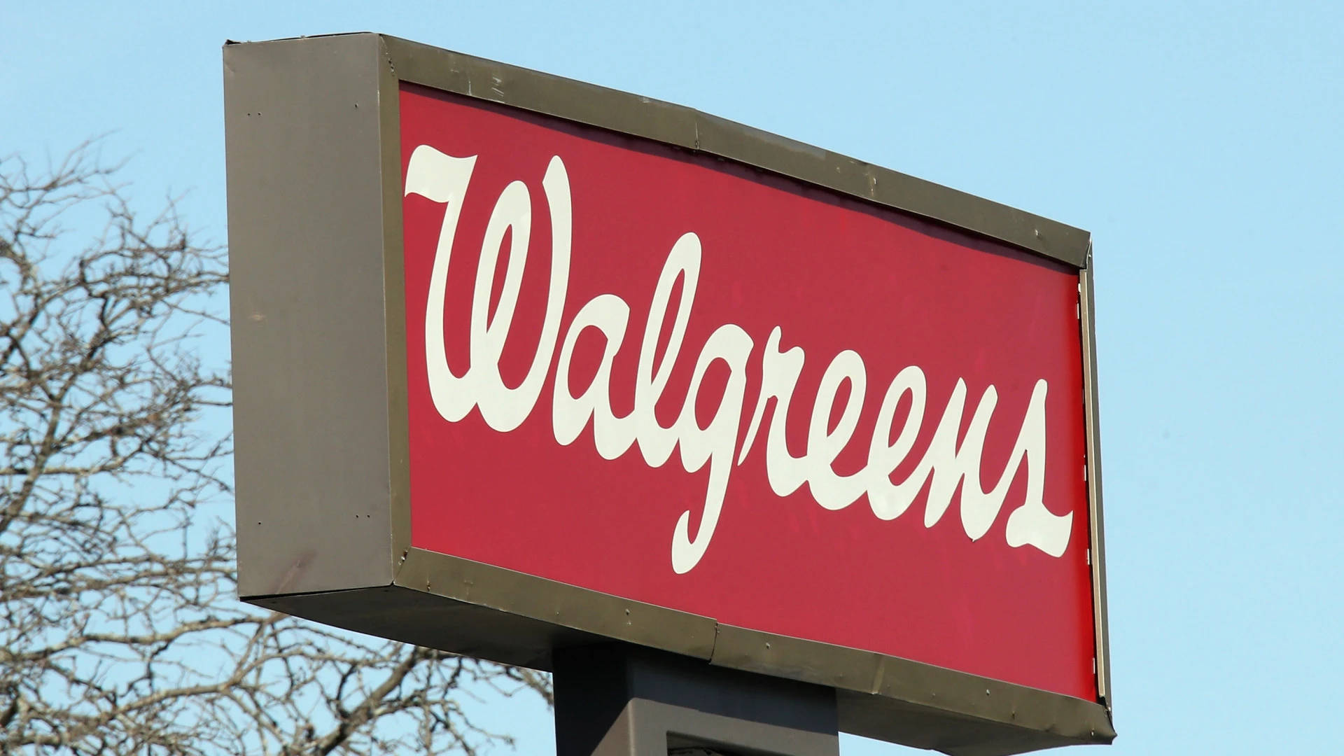 Walgreens商店招牌，紅色背景白色字體，背景為藍天和光禿的樹枝。