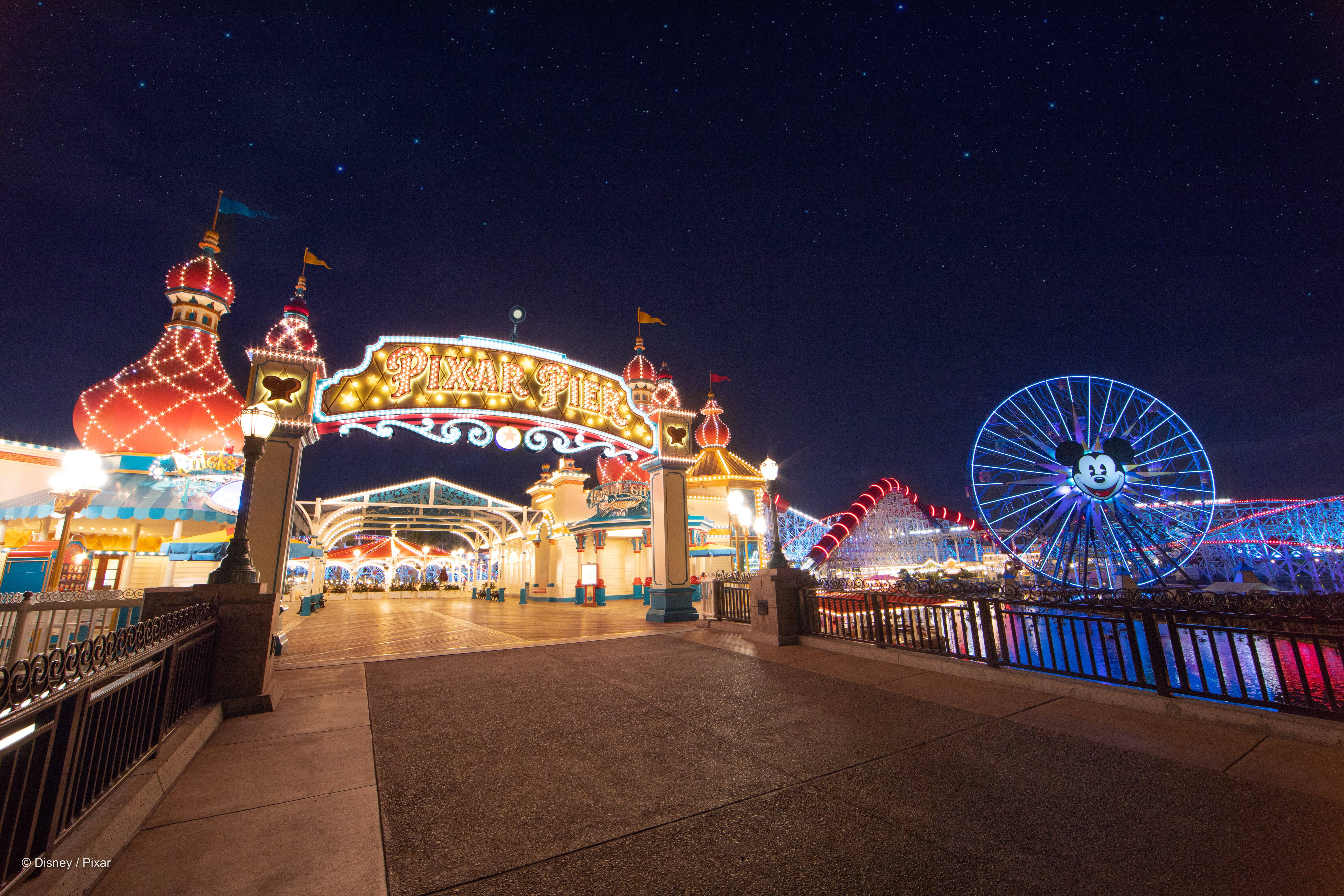 華特迪士尼世界皮克斯碼頭夜景 壁紙 — Pixar Pier 在夜晚星空下閃耀，有米奇老鼠摩天輪和色彩繽紛的遊樂設施。