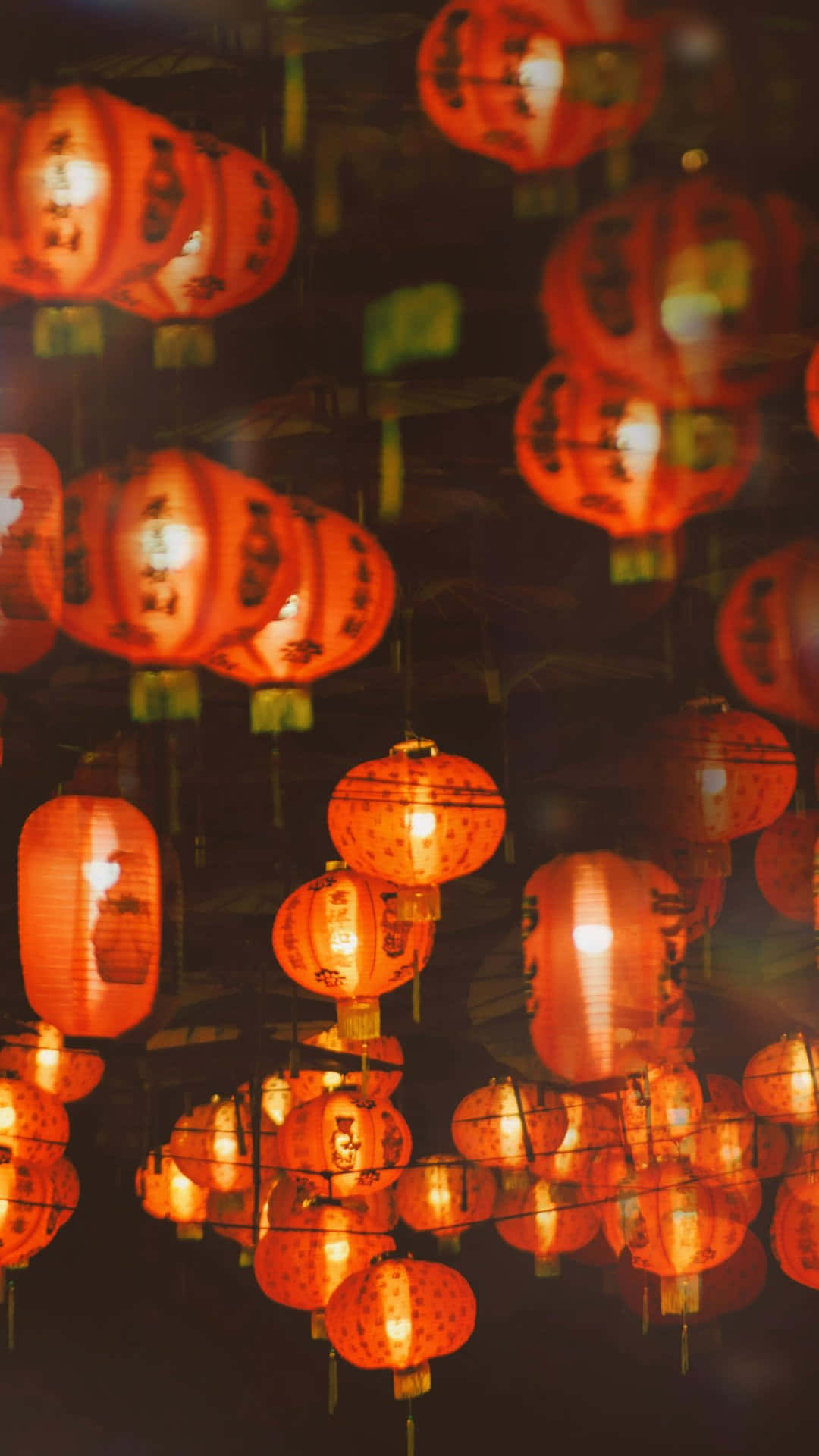  壁紙 — 溫暖發光的紅色燈籠密集地懸掛在黑暗中，投射出柔和的光線，營造出節日氣氛。