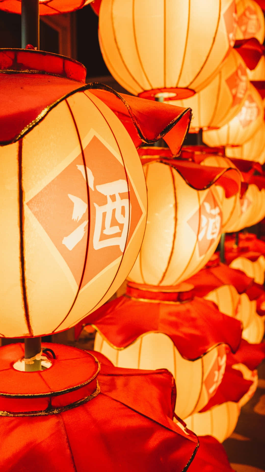  壁紙 — 溫暖發光的紅色燈籠，帶有白色中文字，排成一排照亮節日夜晚場景。