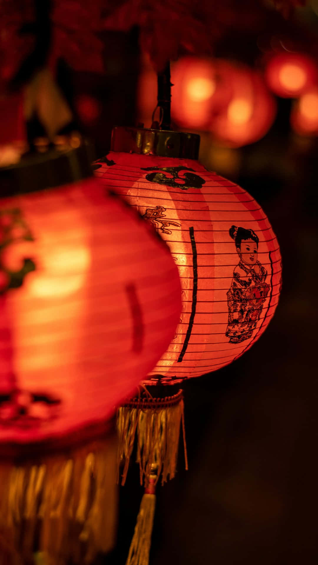  壁紙 — 溫暖發光的紅色紙燈籠，帶有傳統中國設計，在黑暗的夜晚背景下柔和地懸掛著。