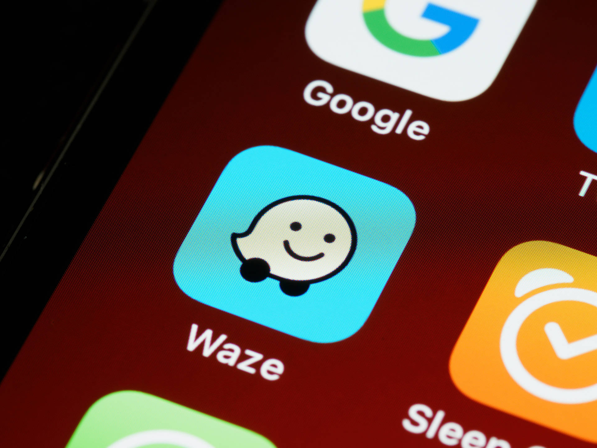 智能手機屏幕顯示Waze應用程式圖標，帶有微笑鬼魂吉祥物。
