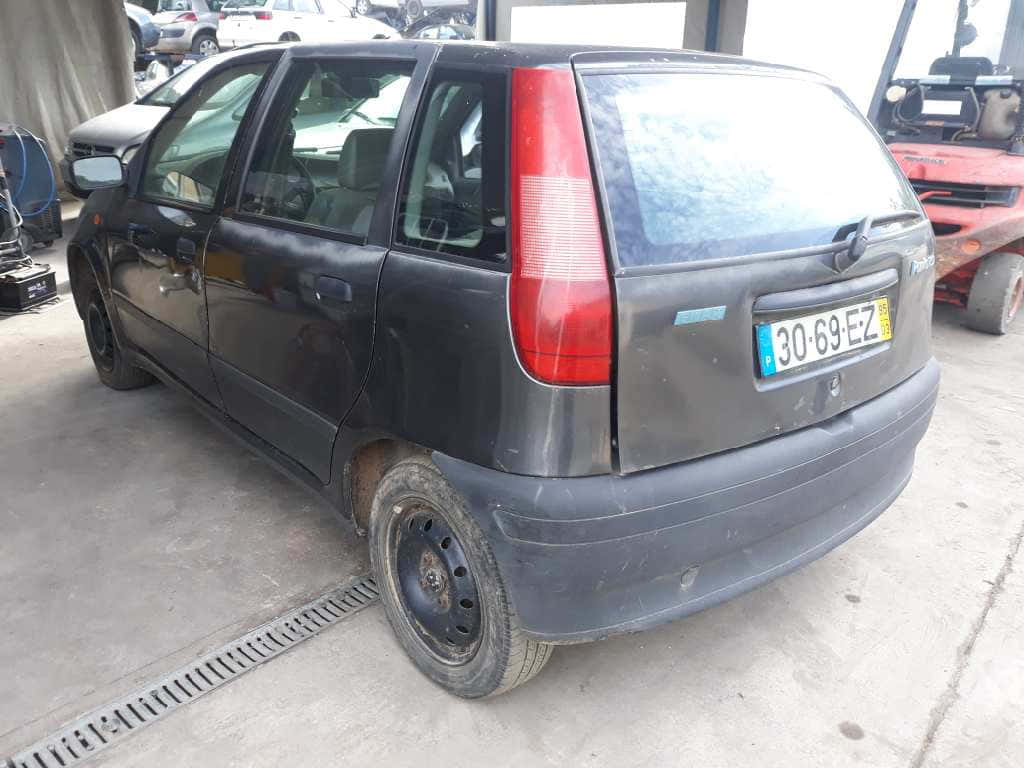 Fiat Punto 桌布 壁紙 — 一輛風化的黑色小型汽車停泊在雜亂的汽車維修車庫中，帶有明顯的磨損和歐洲車牌。