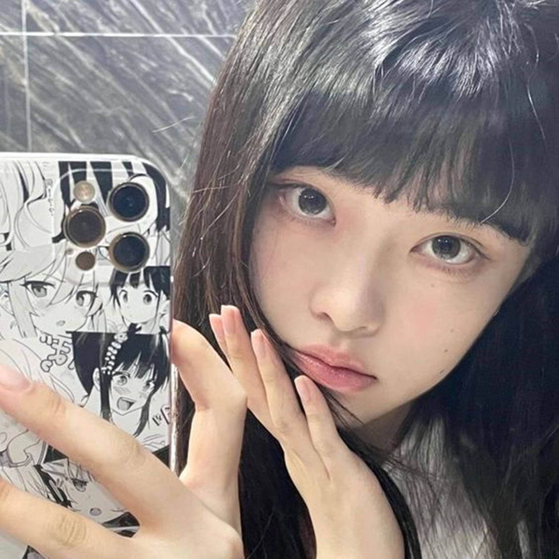 年輕女子拿著帶有動漫角色手機殼的手機對著鏡子自拍