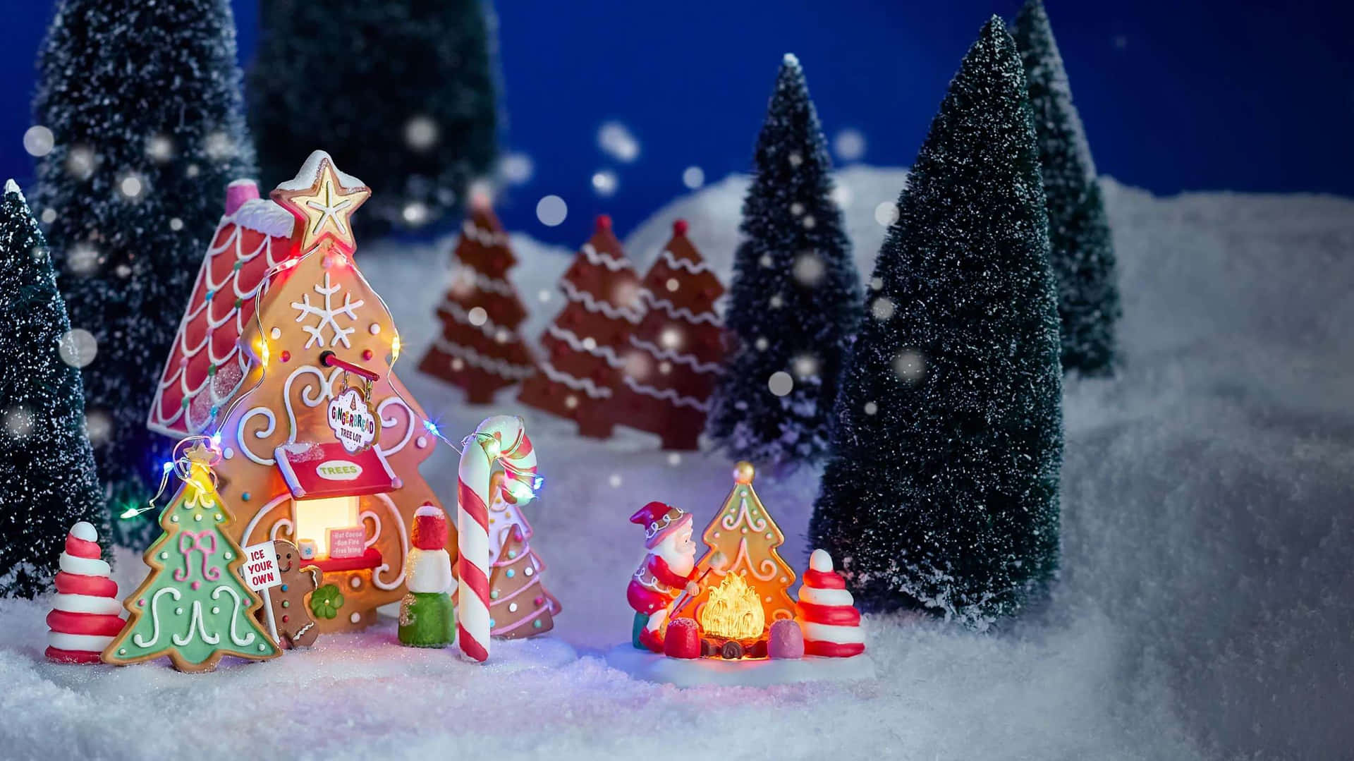  壁紙 — 一個奇特的薑餅村在雪夜天空下閃爍著節日燈光，周圍環繞著微型松樹。