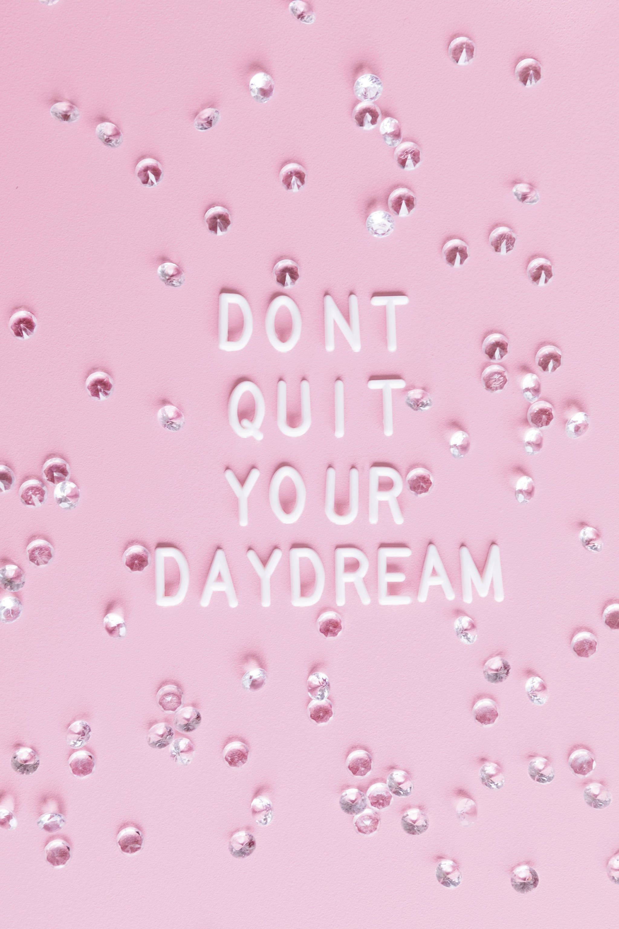 粉紅色背景，白色3D文字寫著 'DON'T QUIT YOUR DAYDREAM'，周圍環繞著銀色水鑽。