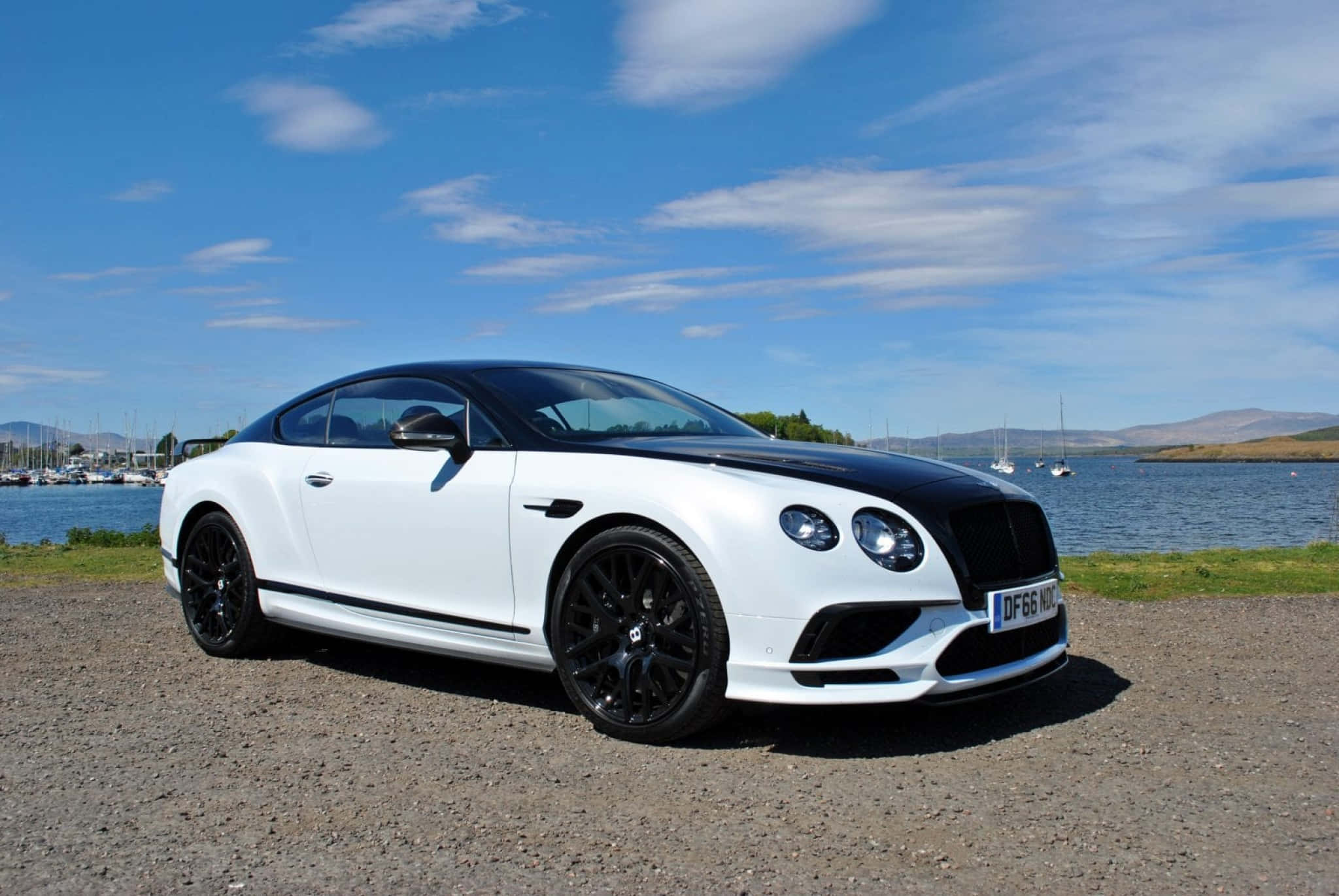 Bentley Continental Supersports 桌布 壁紙 — 一輛白色 Bentley Continental GT 帶有黑色點綴，停在寧靜湖邊的碎石地上，天空湛藍，白雲點點。