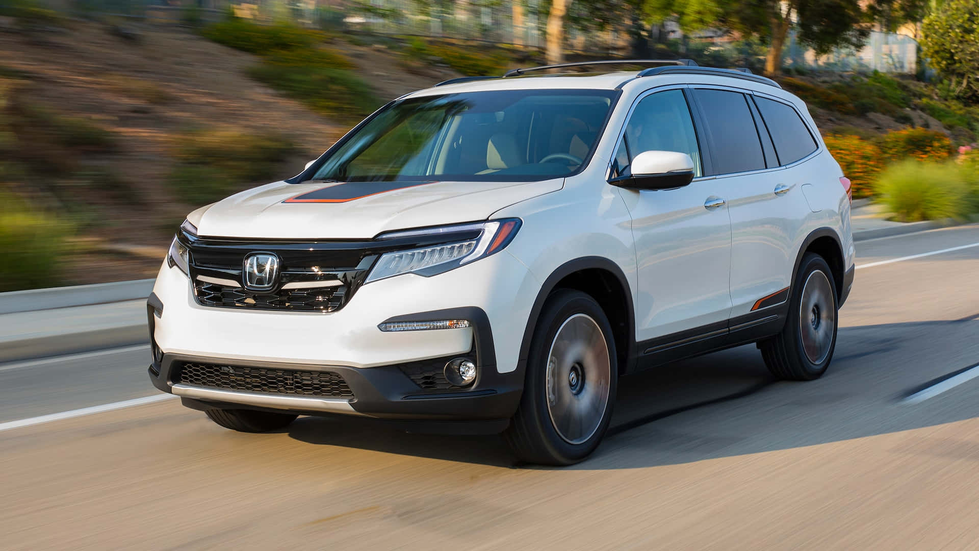 Honda Pilot 桌布 壁紙 — 一架白色本田 Pilot SUV 在陽光明媚的高速公路上行駛，背景是模糊的綠樹和山丘。