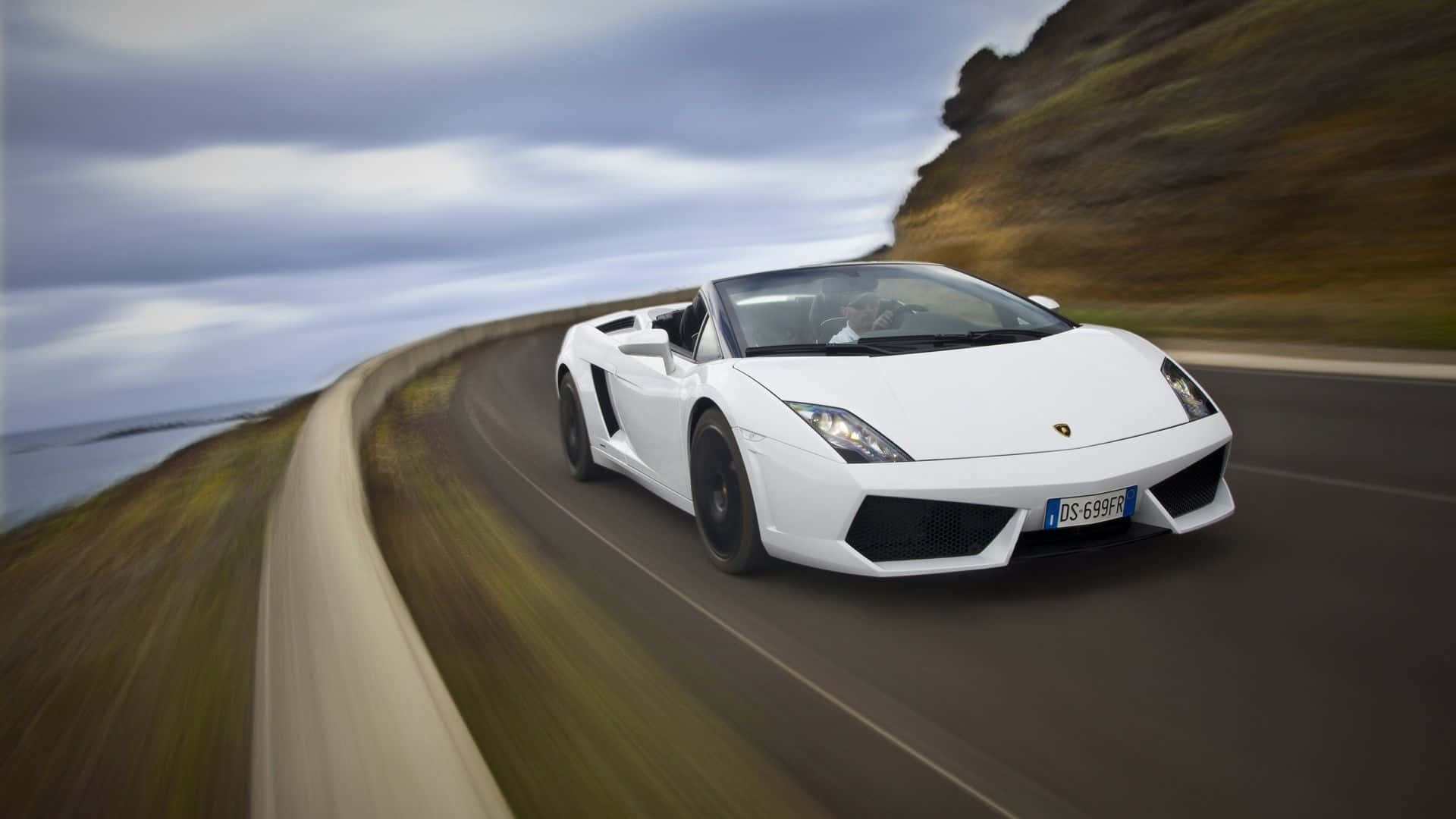 Lamborghini Gallardo 桌布 壁紙 — 一輛白色林寶堅尼Gallardo Spyder沿著海岸公路疾馳，帶有動態模糊和陰天。