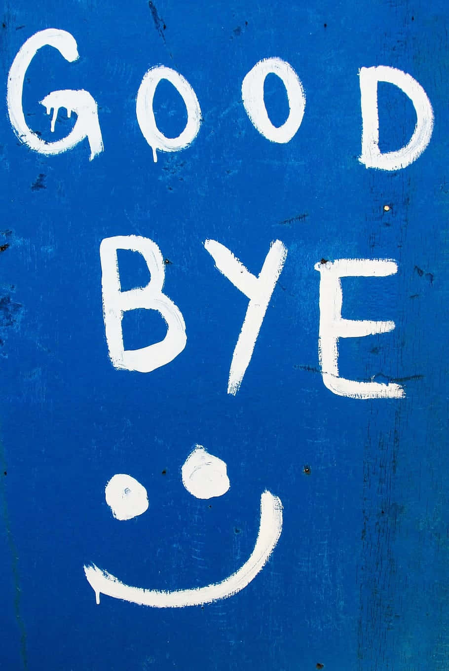  壁紙 — 在帶有紋理的藍色表面上，白色塗鴉「GOOD BYE」和笑臉。