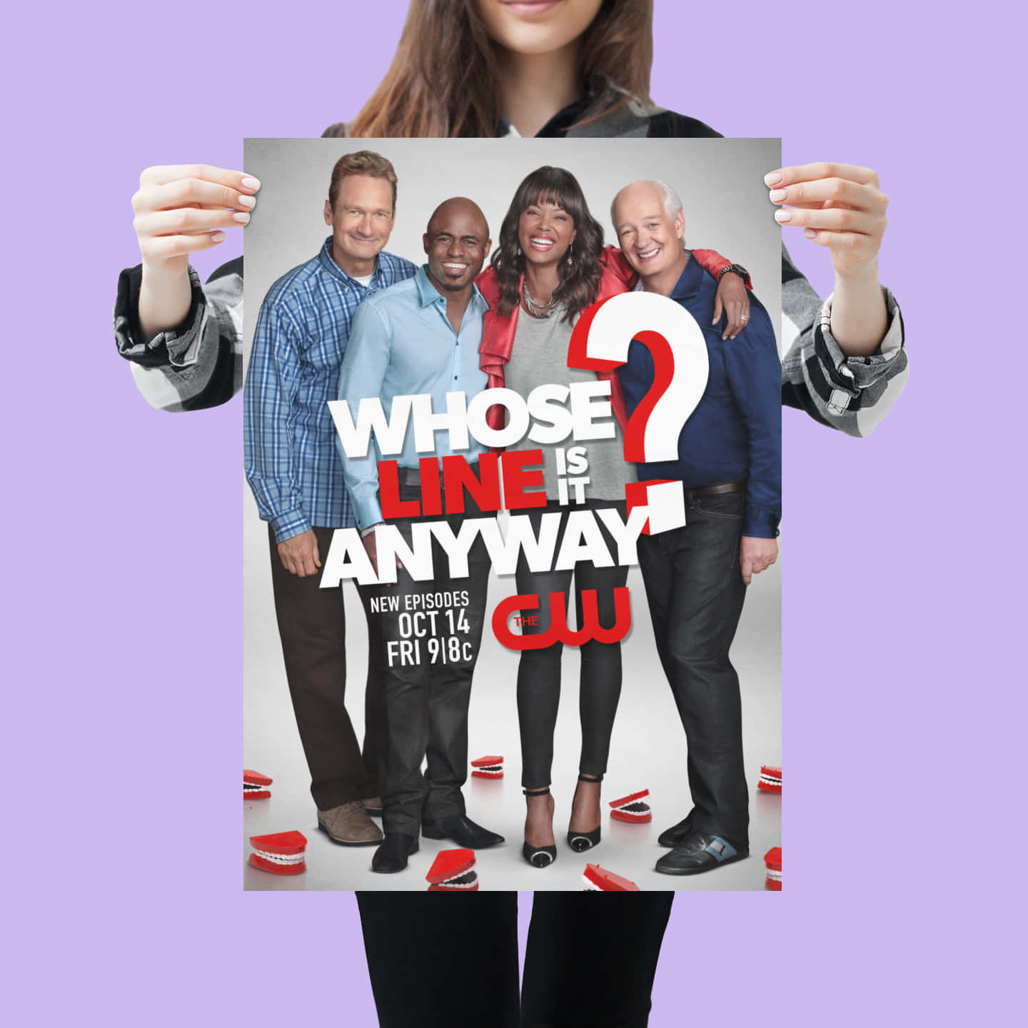 一個人手持《Whose Line Is It Anyway?》電視節目海報，海報上有四位微笑的演員。