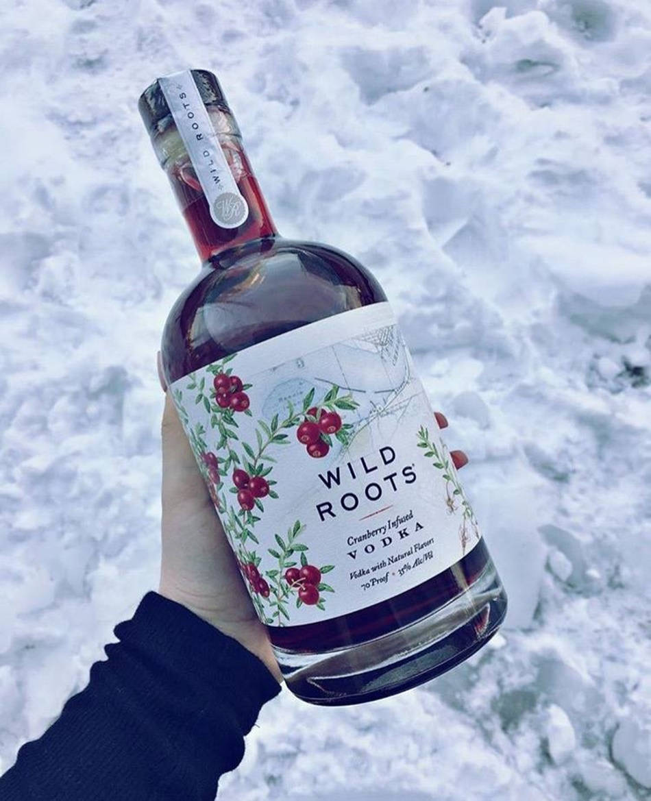 手在雪中拿著蔓越莓伏特加酒瓶