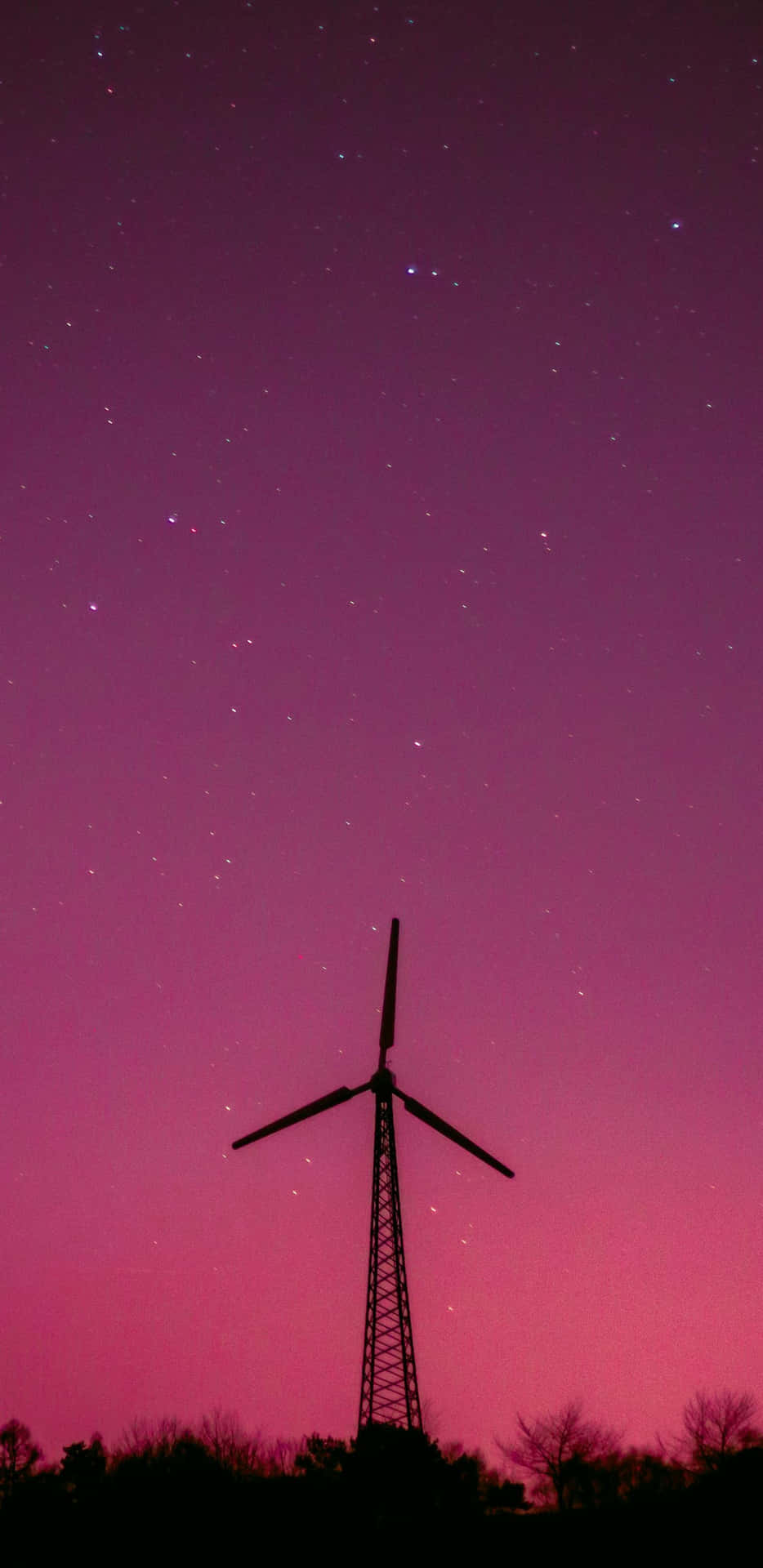  壁紙 — 一座風力渦輪機在充滿活力的洋紅色星空下呈現為黑色剪影。