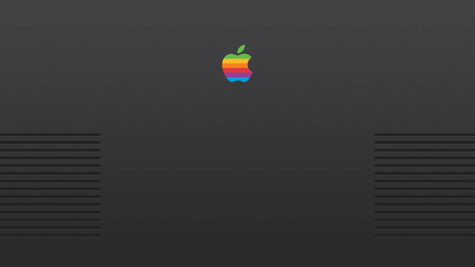 復古彩虹Apple標誌在深灰色筆記本電腦蓋上，帶通風槽。