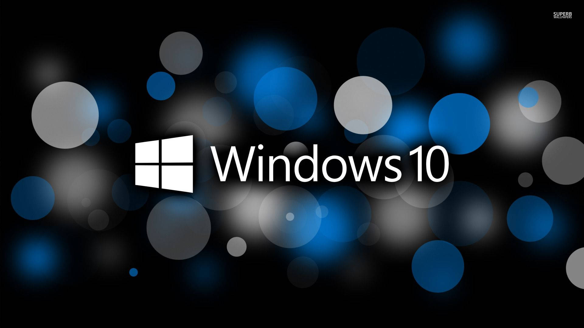 Windows 10 高清光點 壁紙 — Windows 10 標誌以白色文字和圖示居中顯示在深色背景上，帶有發光的藍色和灰色散景圓圈。