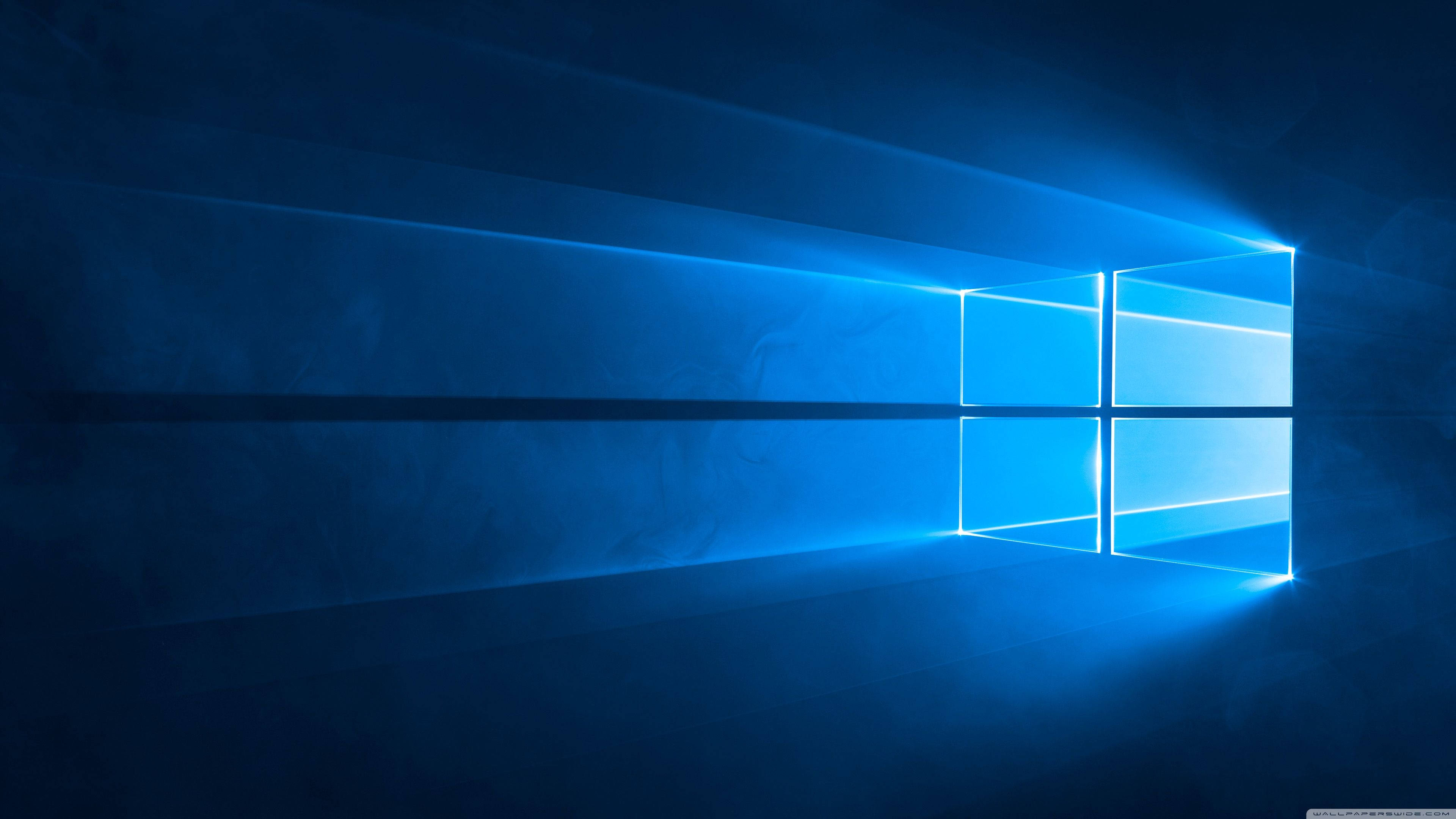 Windows 10圖形藝術 壁紙 — 一個發光的藍色窗戶標誌在黑暗的抽象空間中散發出帶有光線條紋的光芒。