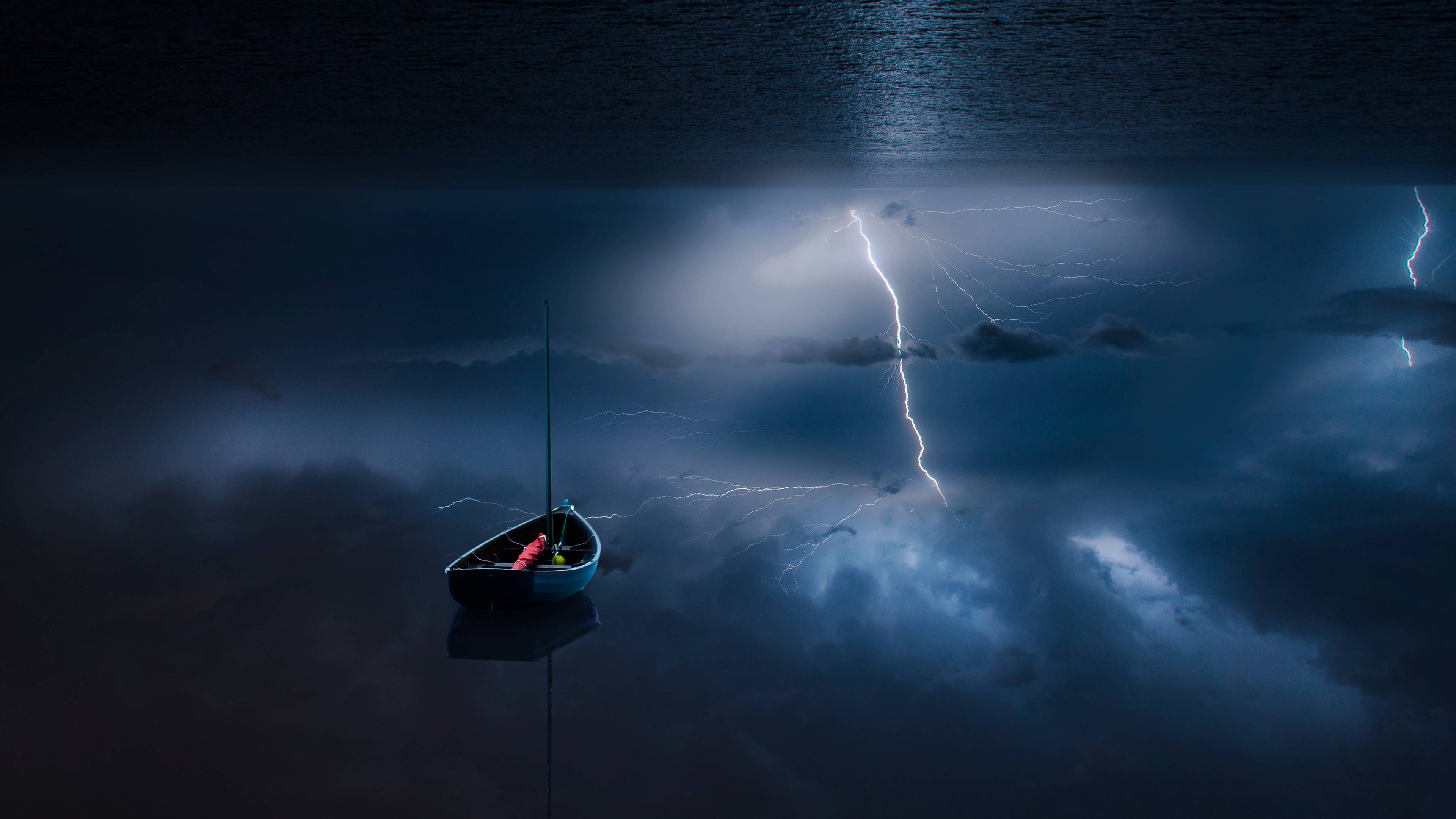 Windows 11 4K 海上雷電 壁紙 — 一艘孤獨的帆船漂浮在暴風雨的湖面上，鋸齒狀的閃電照亮了上方烏黑的雲層。