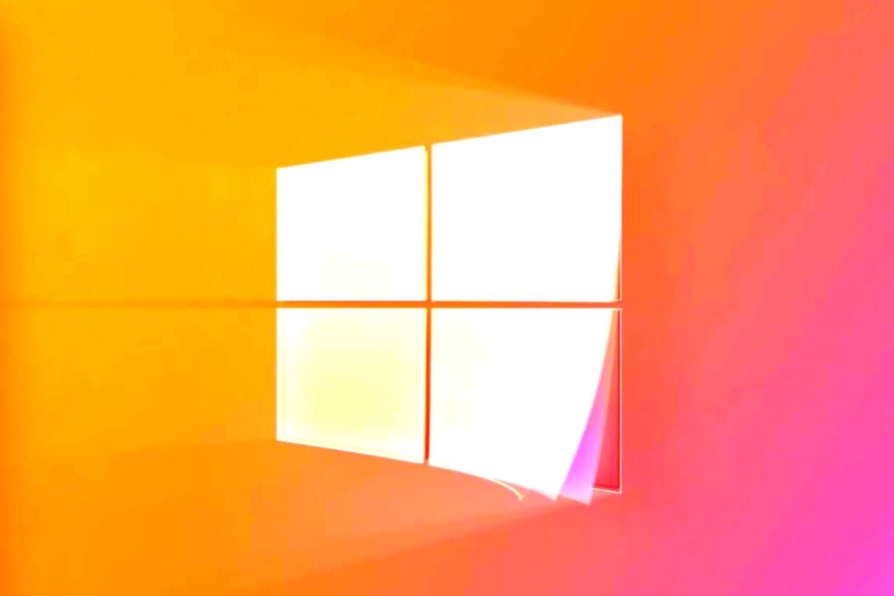 Windows 11 橙粉漸層 壁紙 — 一扇發光的四格窗戶，將明亮的光線投射到橙色和粉紅色漸變的牆壁上。