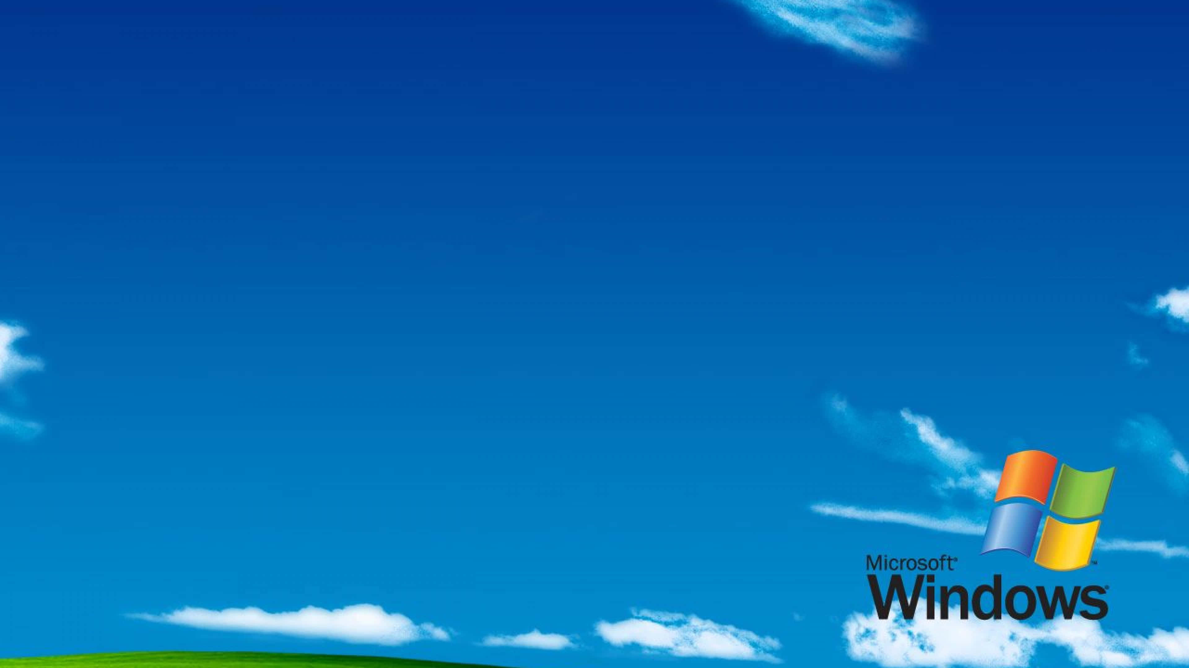 Windows XP 標誌 壁紙 — Microsoft Windows 標誌下，充滿活力的藍天、蓬鬆的白雲和綠色山丘。