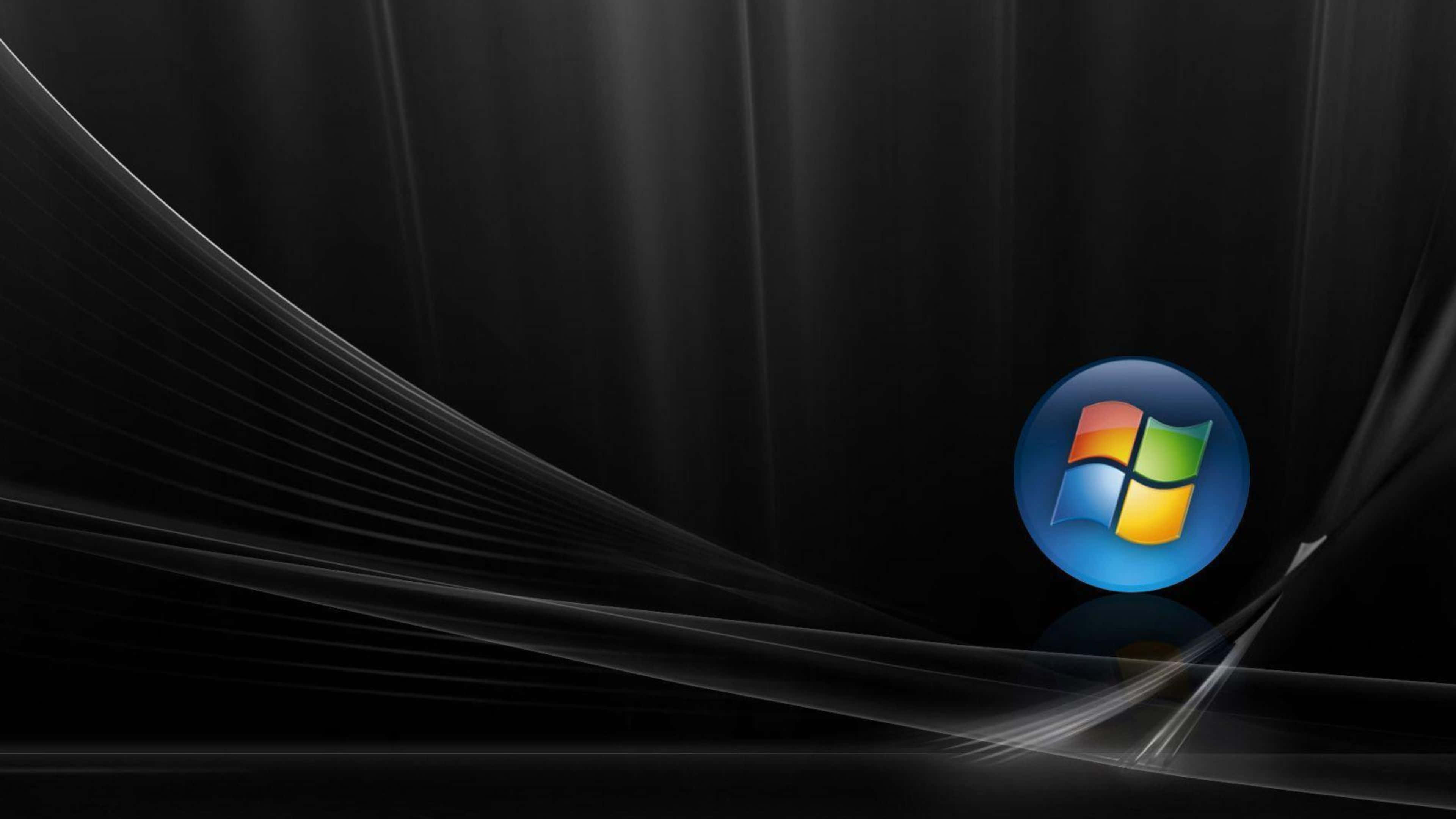 Windows Vista 桌布 壁紙 — Windows 標誌在光滑的黑色背景上發光，伴隨著流動的銀色光條，營造出現代數位美學。