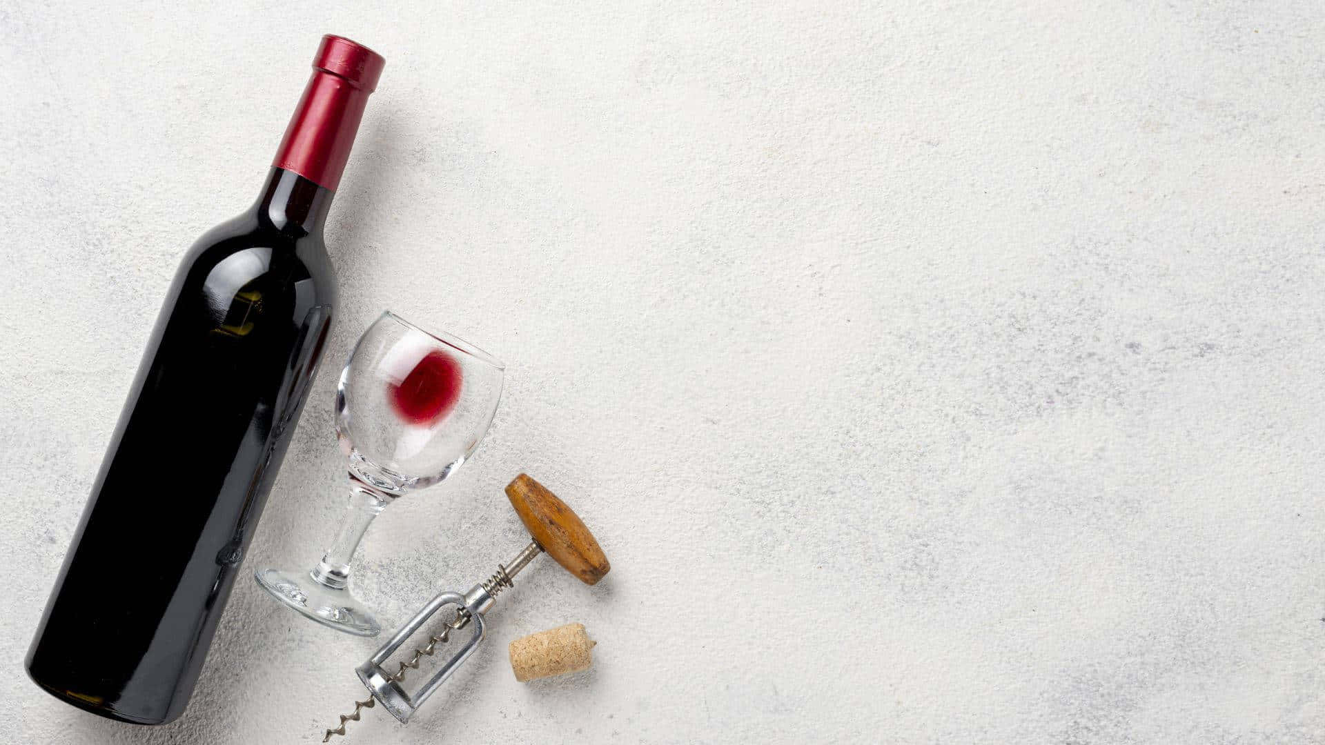 紅酒瓶、玻璃開瓶器和軟木塞放在有紋理的灰色表面上。