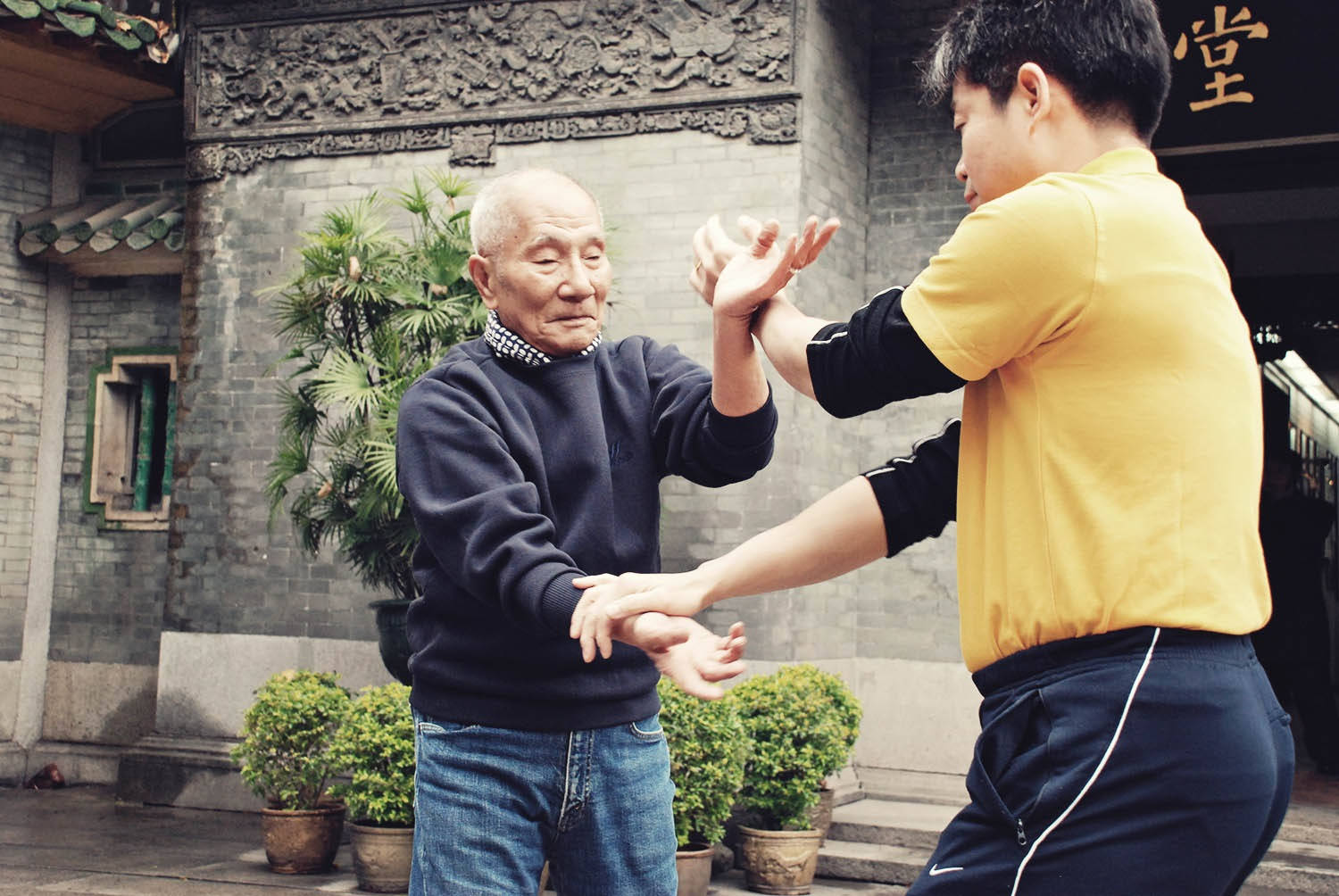 年長武術大師在傳統庭院中教導年輕學生。