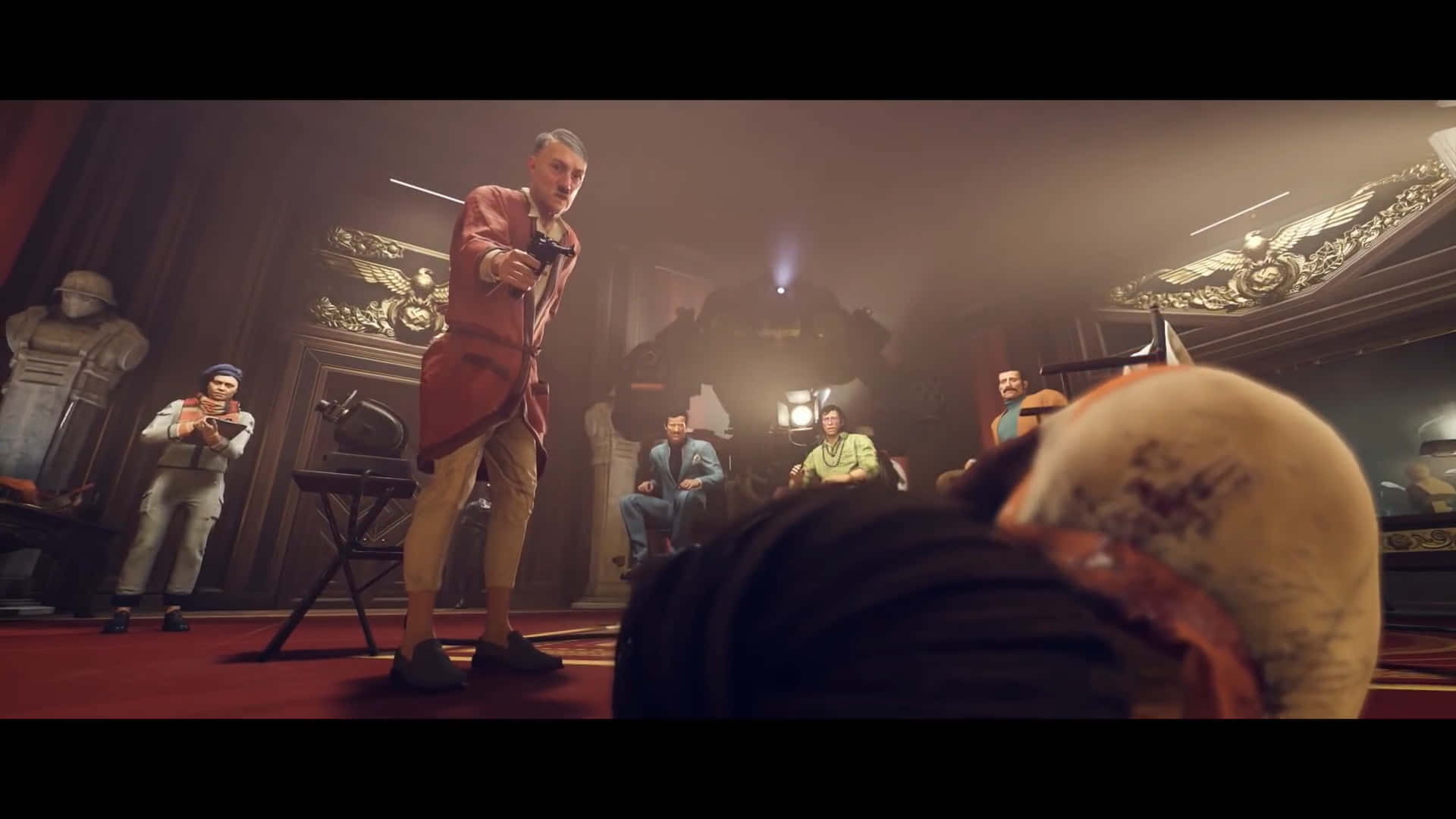 《Wolfenstein II》遊戲背景：羅納德·雷根 壁紙 — 一名身穿紅色外套的男子在燈光昏暗、裝飾華麗的劇院中，將手槍瞄準一個俯臥的人物，周圍有坐著的觀眾。