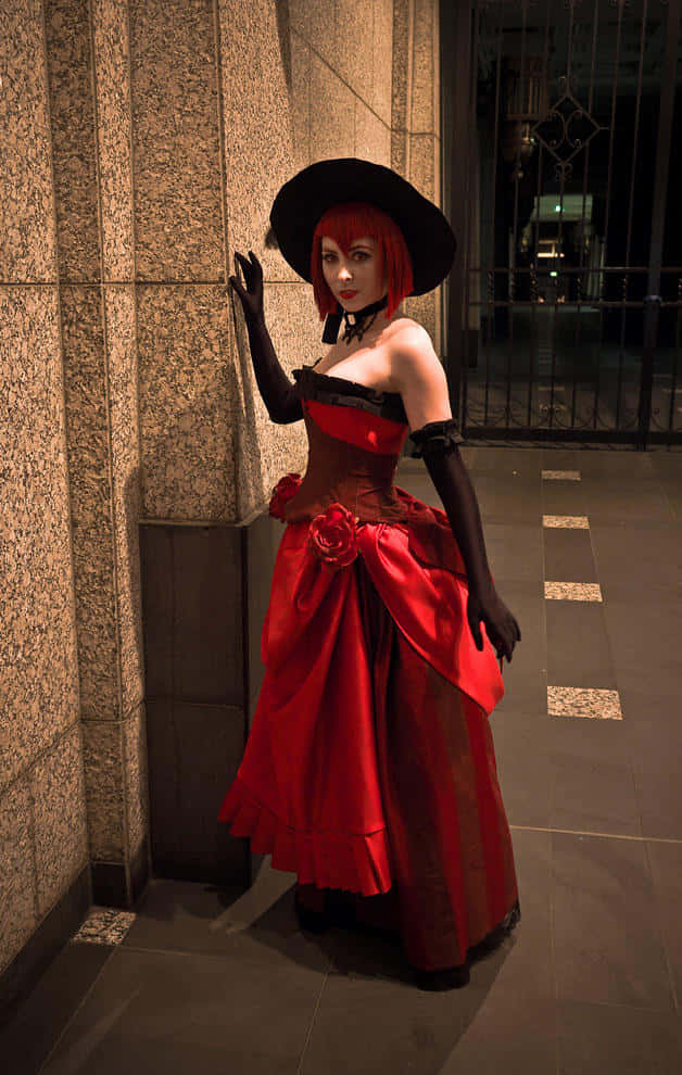 Madam Red 桌布 壁紙 — 一位身穿搶眼紅黑維多利亞長裙、戴著寬邊帽子的女士，在夜晚昏暗的城市小巷中靠著石柱。