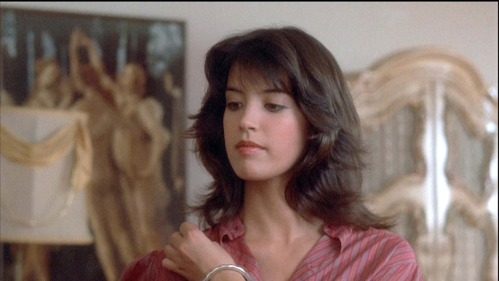 Phoebe Cates 桌布 壁紙 — 一位留著及肩棕色頭髮、身穿紅色條紋襯衫的女性，在光線柔和、擺設華麗的房間裡若有所思地凝視著。