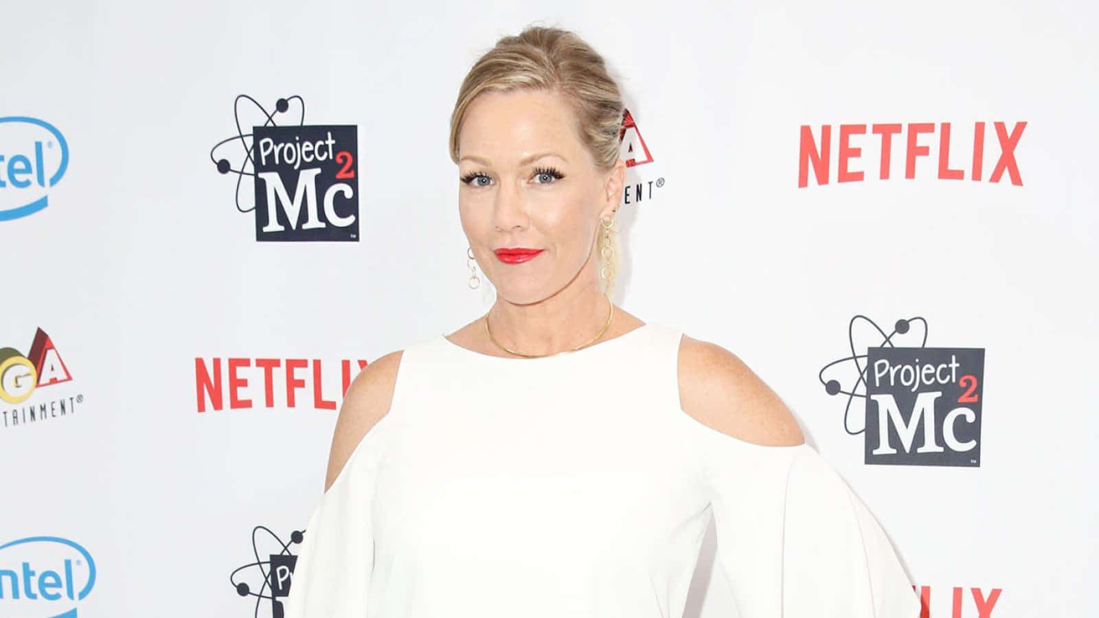 Jennie Garth 桌布 壁紙 — 一位身穿白色露肩連衣裙的女性在紅地毯活動中自信地擺姿勢，身後有Netflix和Project Mc2的標誌。