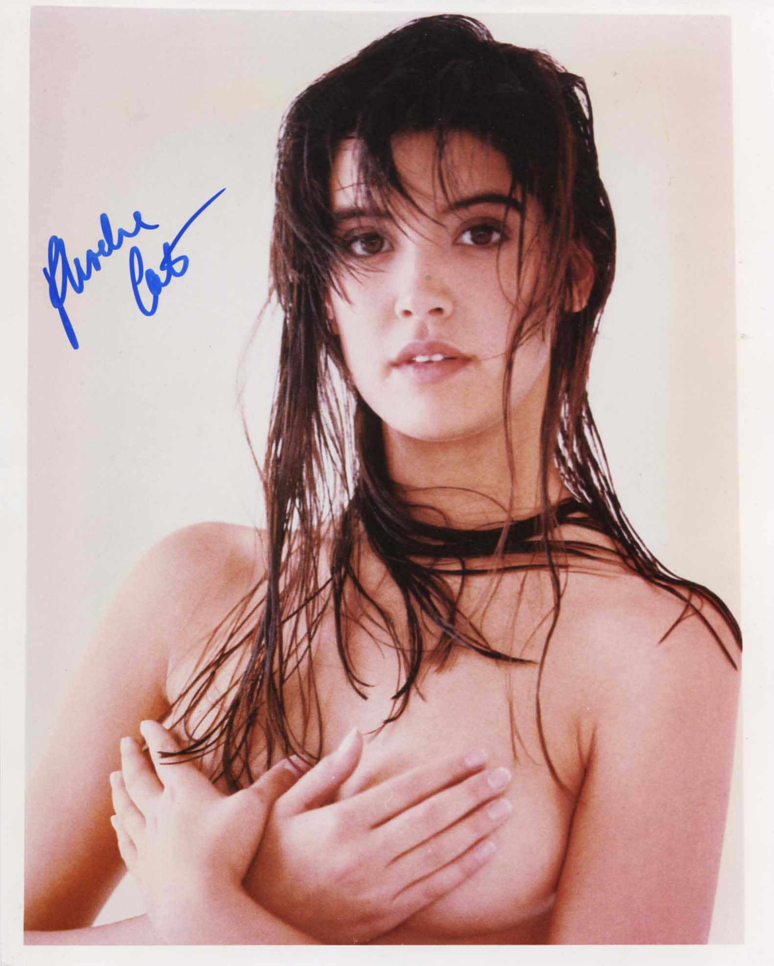 Phoebe Cates 桌布 壁紙 — 一位擁有濕黑髮和黑色頸鏈的女性，在純色背景前用雙手遮蓋胸部。