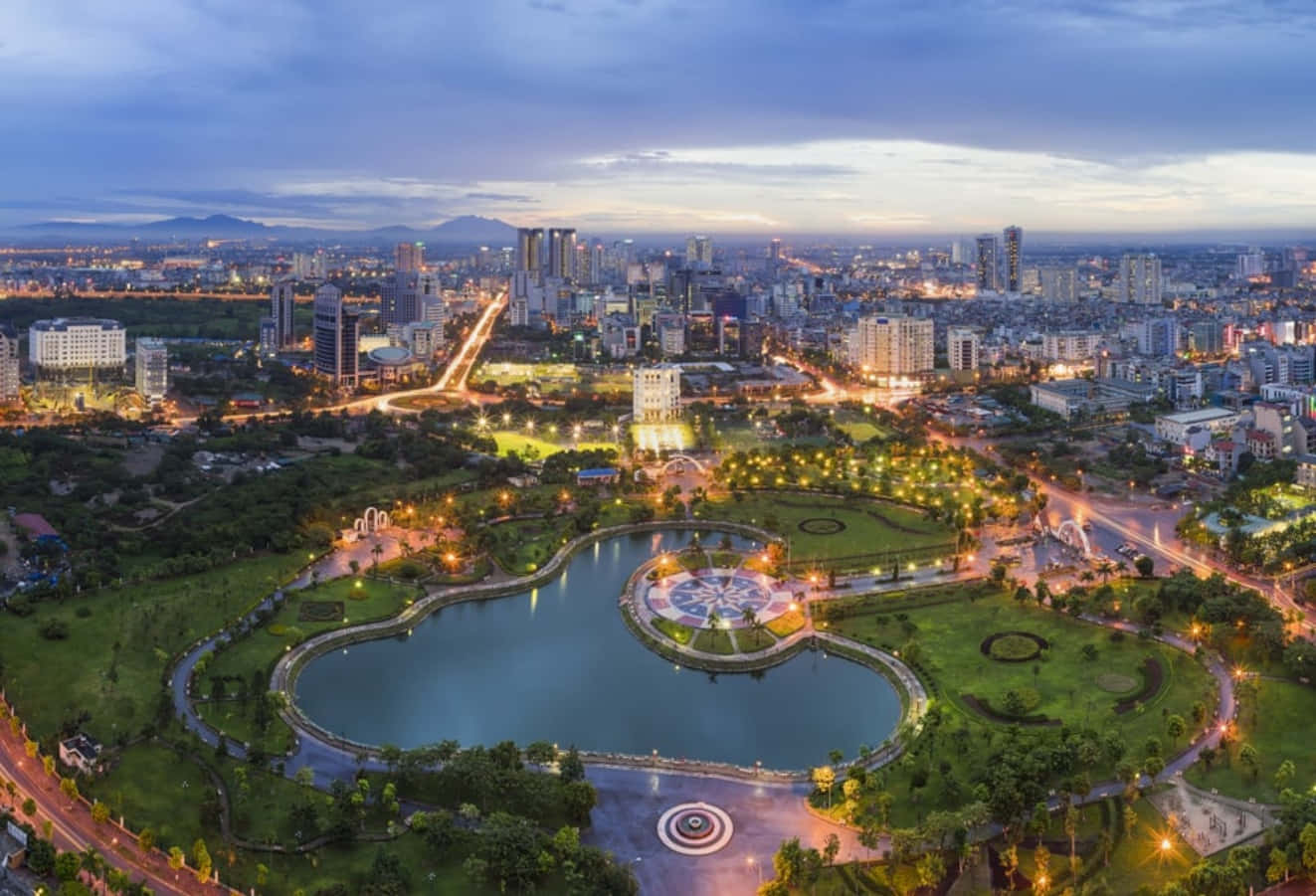 黃昏時分，被建築物和綠樹環繞的心形湖泊點亮的城市公園。