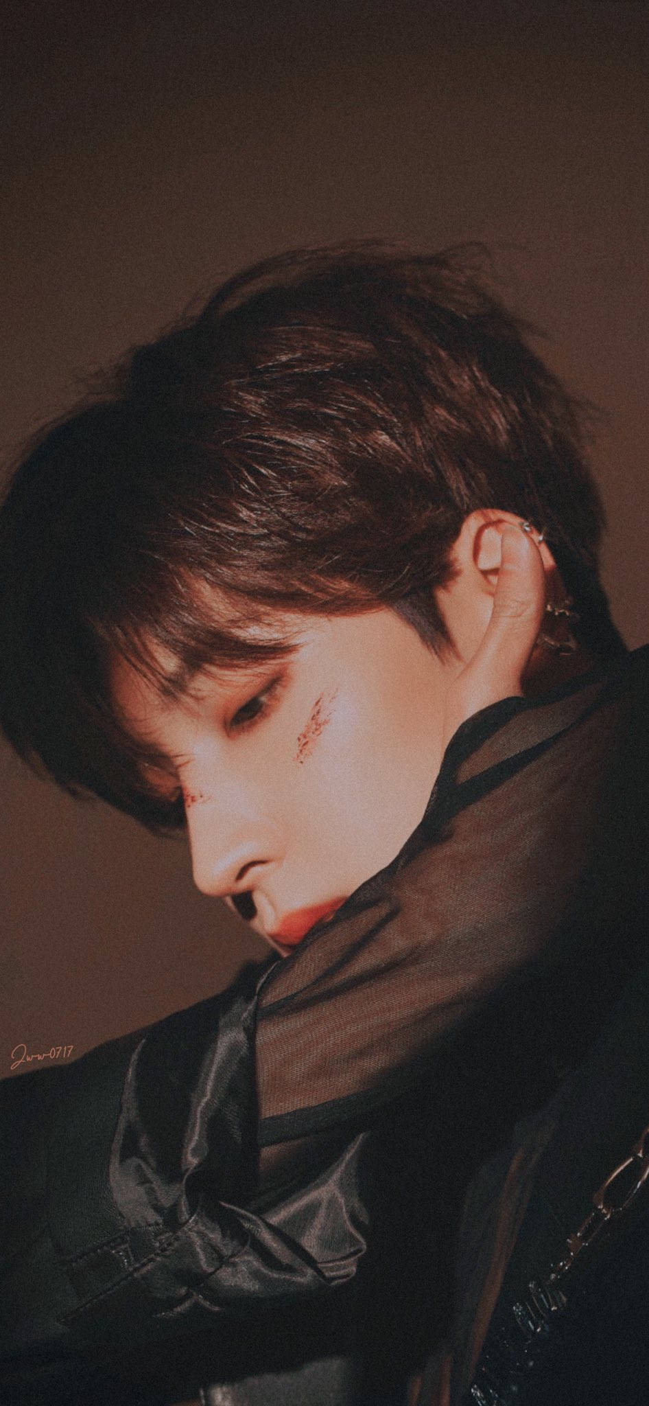 Wonwoo 側面輪廓 壁紙 — 一位深色頭髮、臉上帶有紅色標記的年輕男子，在昏暗、情緒化的肖像中向下凝視。