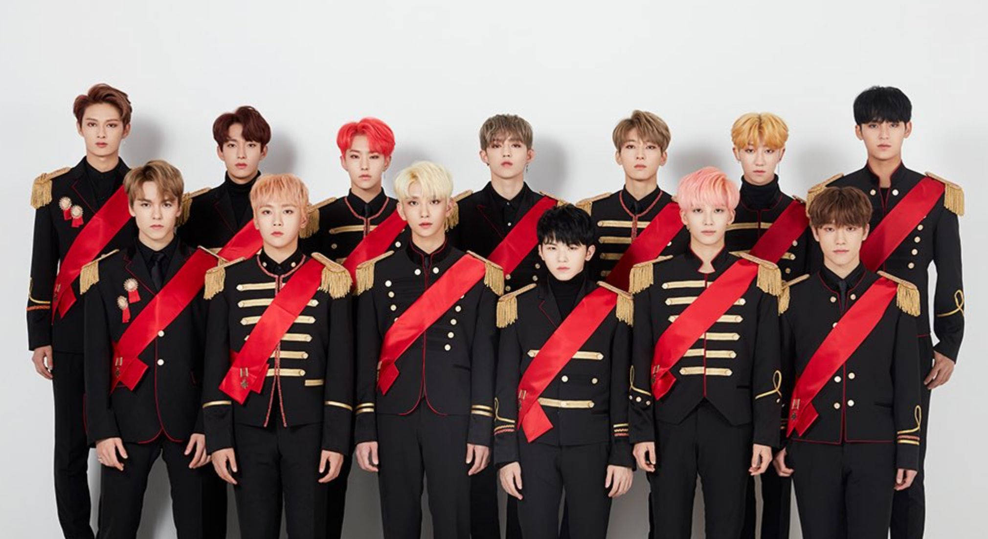 Wonwoo 與SVT成員同框 壁紙 — 一群身穿黑色軍裝風格制服、配紅色肩帶和金色飾邊的年輕男性，在純白背景前擺姿勢。