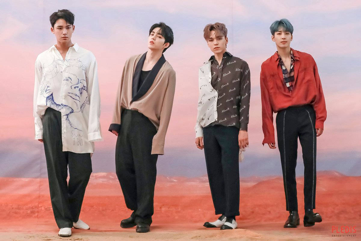 Wonwoo 與嘻哈隊伍 壁紙 — 四位時尚男士穿著時尚服裝，自信地站在紅色沙漠景觀上超現實的粉紅色和橙色天空前。