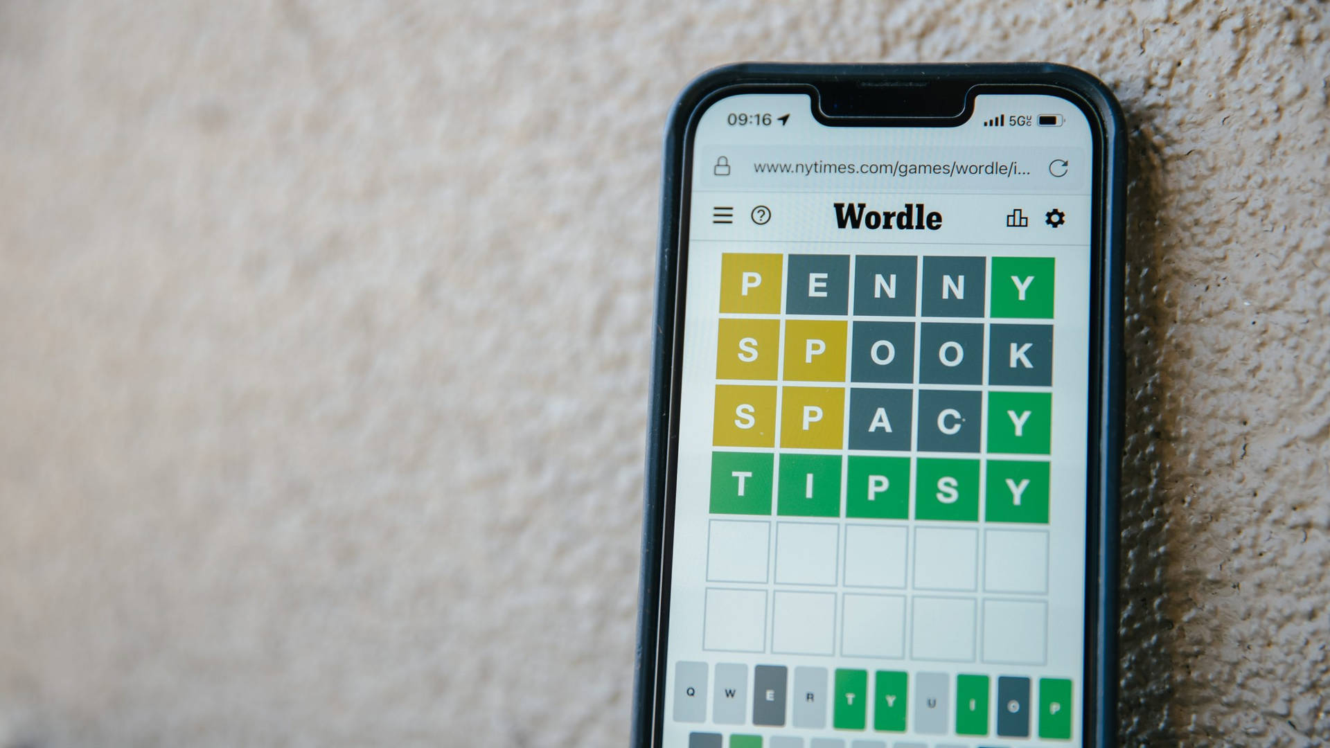 智能手機在紋理牆上顯示Wordle遊戲及已解決謎題。