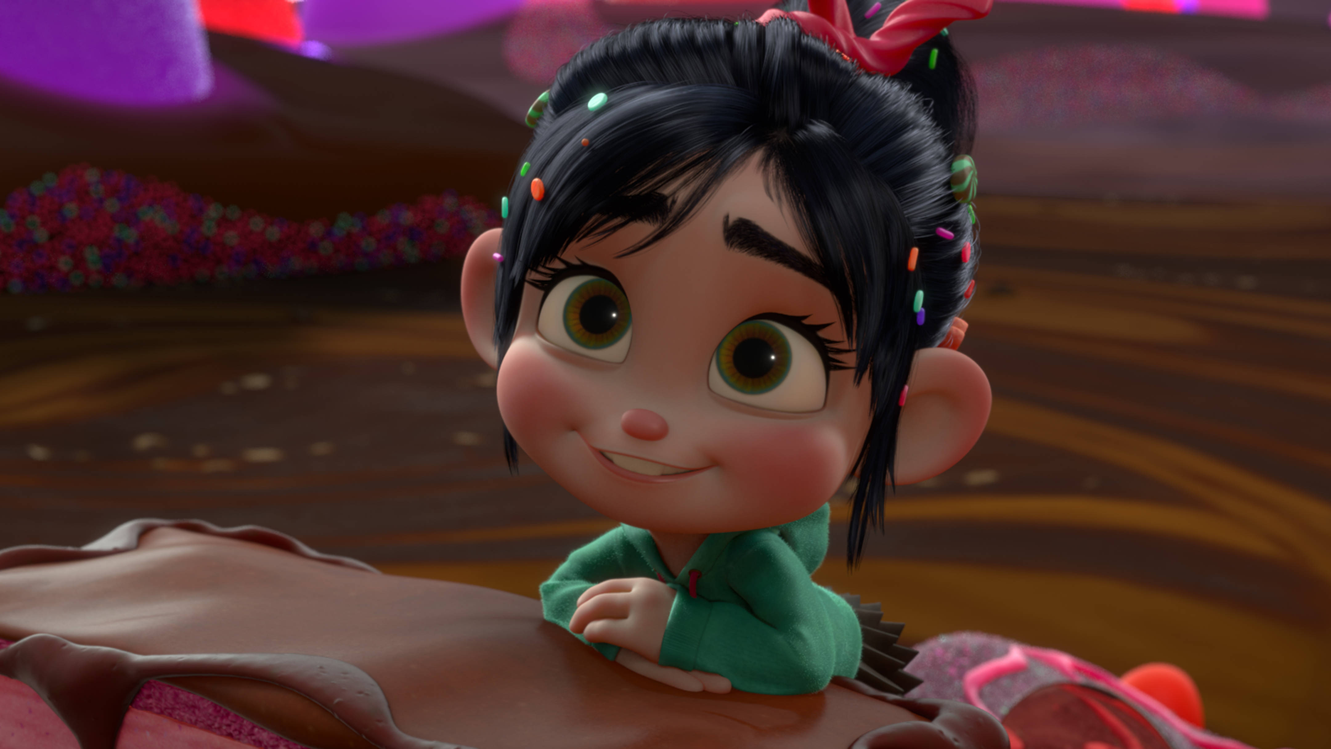 《 wreck-it ralph 》迷人的凡妮莎 壁紙 — 一個開心的動畫女孩，黑髮綠眼，在糖果主題世界中微笑著靠在朱古力表面上。