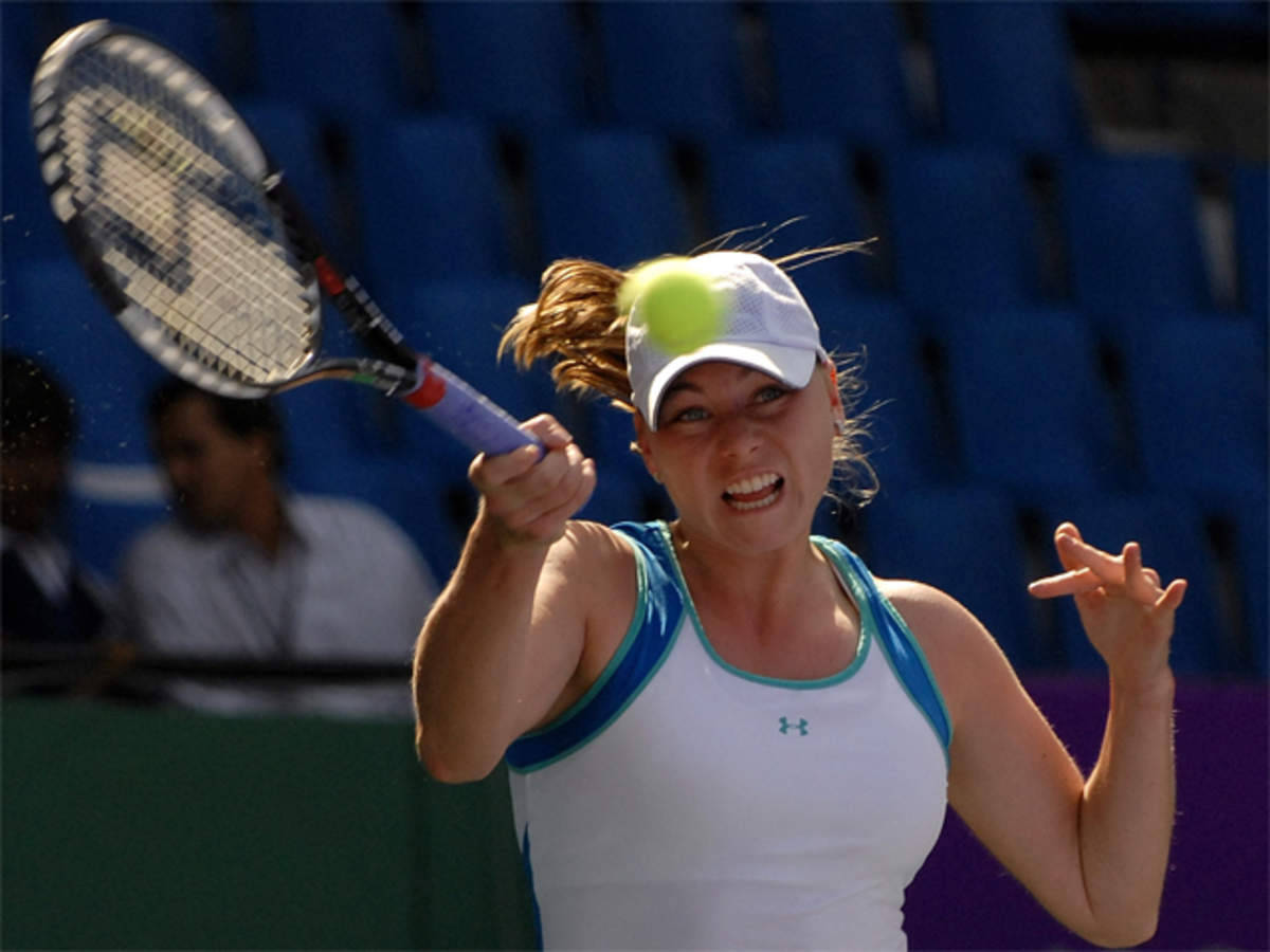WTA網球選手維拉·茲韋列娃 壁紙 — 一名女網球運動員在藍色體育場座位的背景下，全神貫注地揮拍擊打一個亮黃色的球。