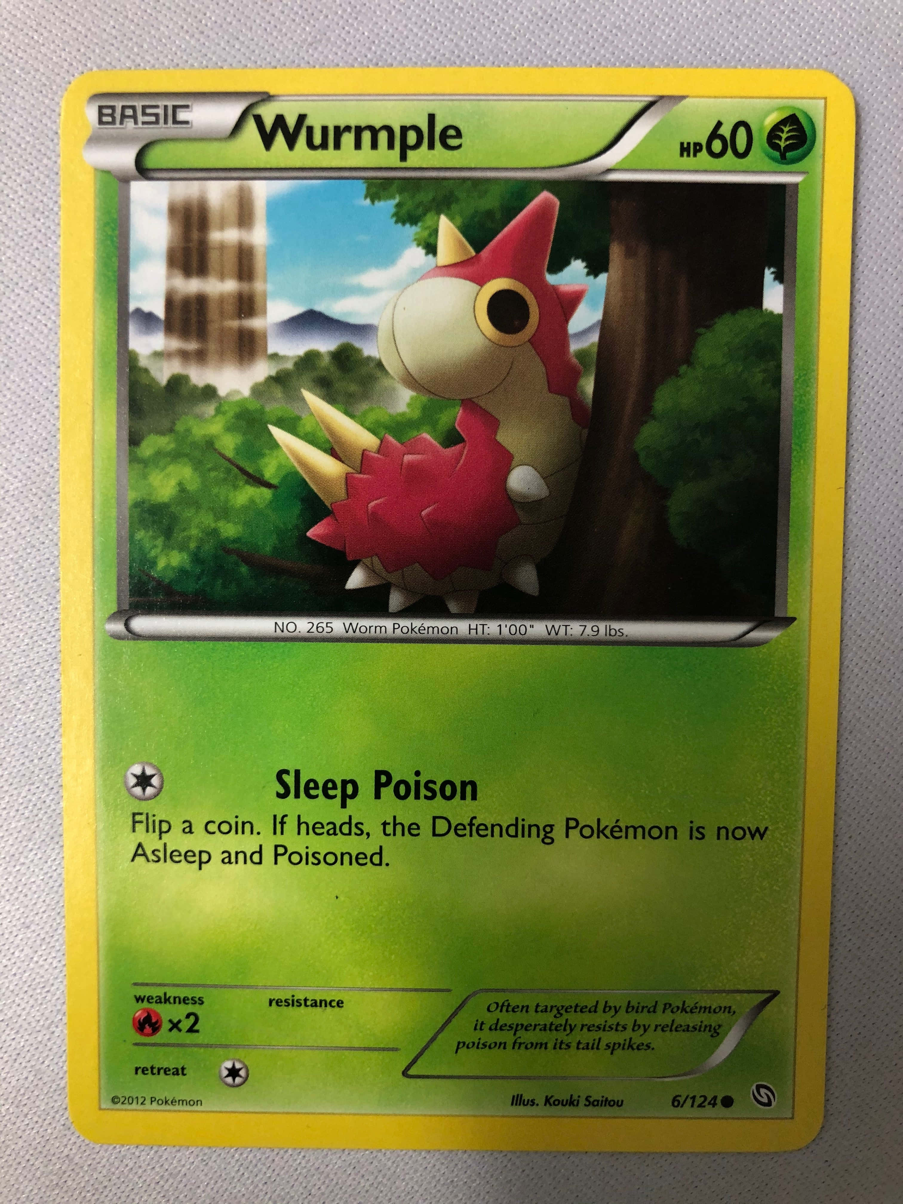 Wurmple 的睡眠毒屬性寶可夢卡 壁紙 — 一張Wurmple寶可夢卡片展示了一隻紅色和米色的毛毛蟲狀生物緊貼在茂密綠色森林中的一棵樹上。