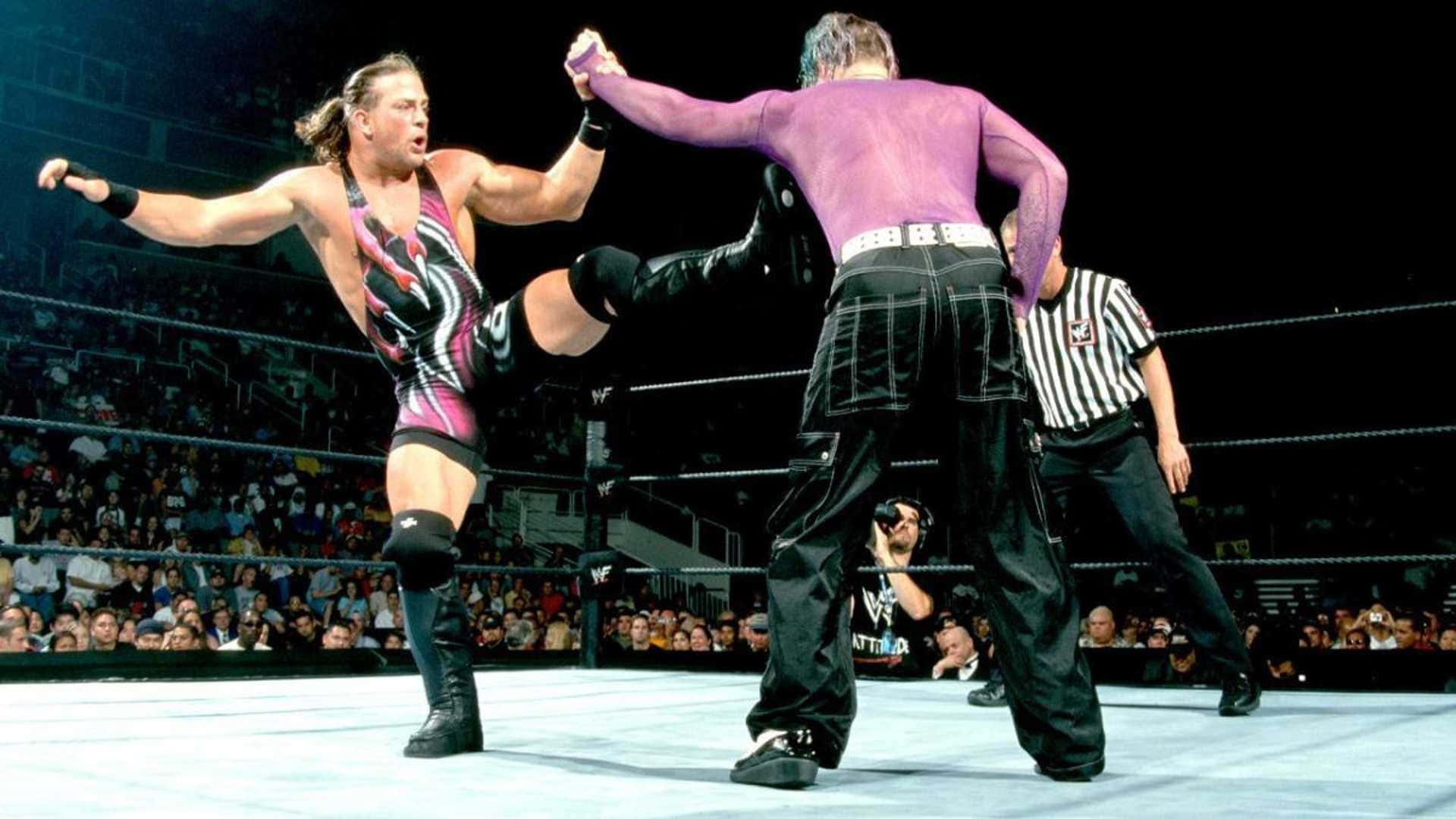 WWE 羅布·范·達姆 2001年夏日狂潮賽事 壁紙 — 兩名摔角手在擂台上交鋒，其中一人使出高踢，裁判則在座無虛席的場館中監視。