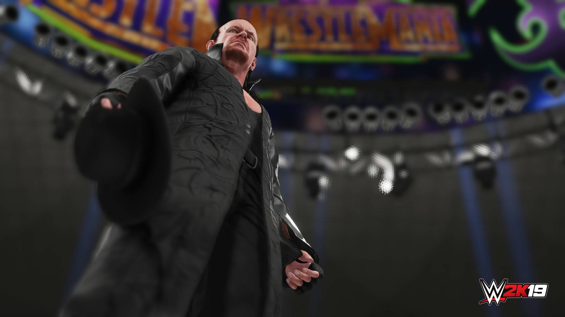 WWE《The Undertaker》遊戲動作場景 壁紙 — 一名身穿黑色外套和高帽的威嚇摔角手在場館燈光下戲劇性地站立，背後有發光的 'WRESTLEMANIA' 標誌。