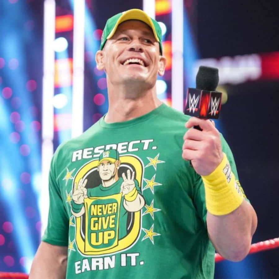 John Cena 桌布 壁紙 — WWE摔角手John Cena身穿綠色'Never Give Up'T恤，在擂台上自信滿滿地手持麥克風。
