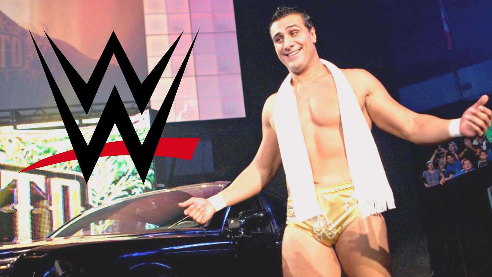 WWE Logo 桌布 壁紙 — WWE摔角手自信微笑，身穿金色短裤，肩上搭着白色毛巾，站在一辆黑色汽车旁。