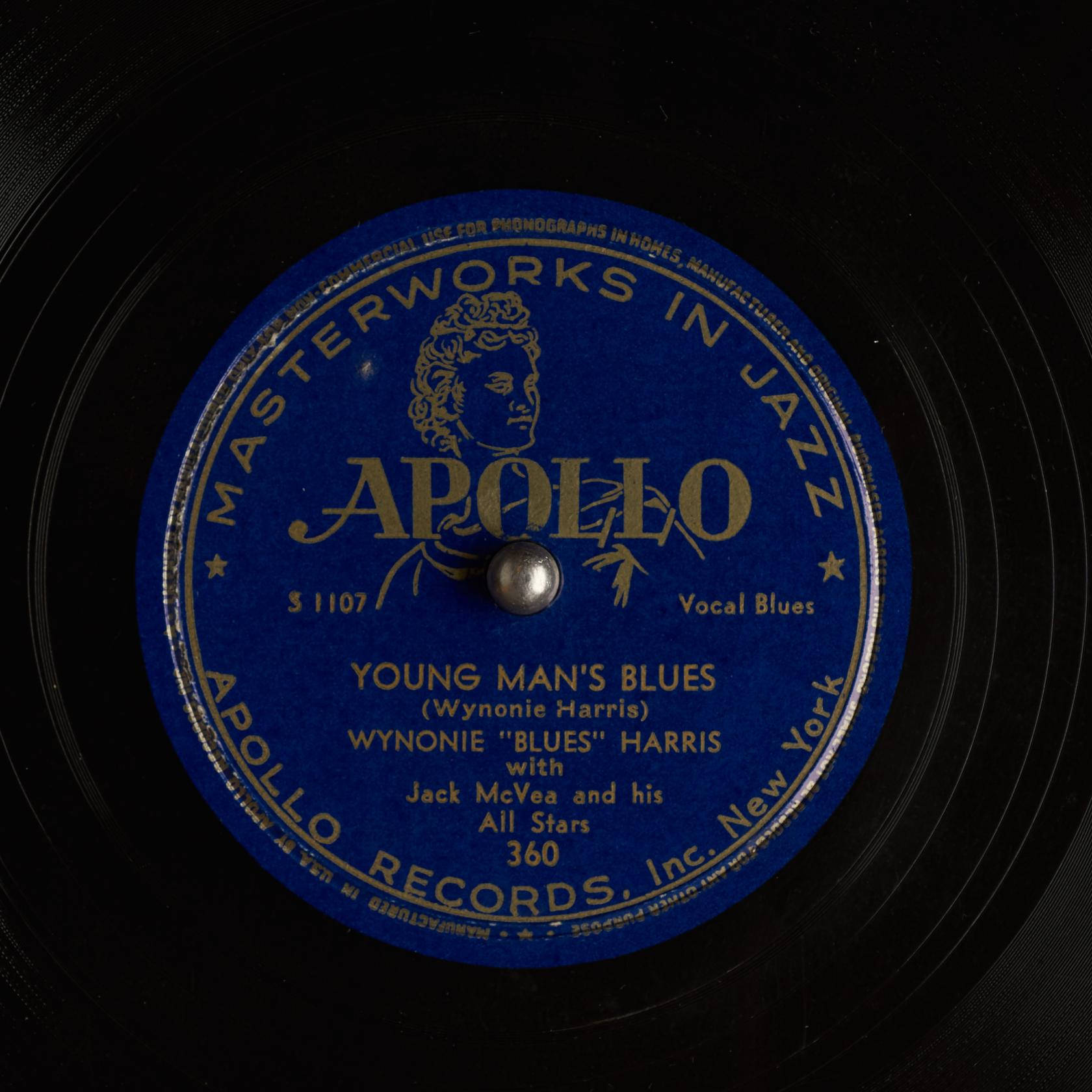 特寫鏡頭：一張復古Apollo Records黑膠唱片標籤，藍色背景配金色文字。