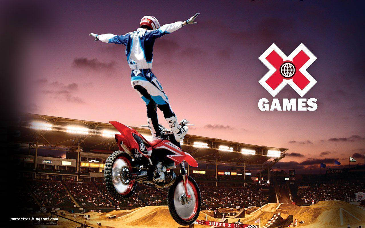 X Games BMX自行車高飛躍起 壁紙 — 一名越野電單車手在黃昏時分，於座無虛席的體育館上空，騎著紅色電單車飛躍，並帶有X Games標誌。